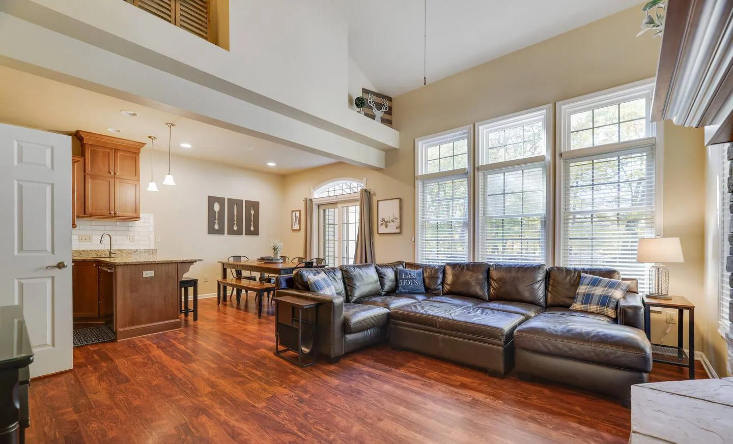 Large leather sectional with tall windows and kitchen beyond at Mountainwoods Memories