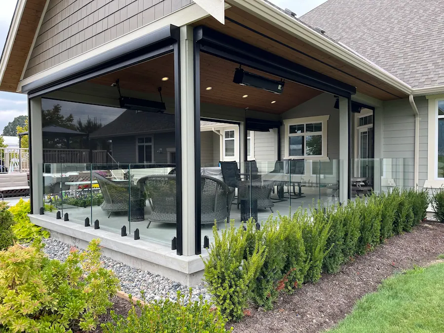 Covered patio with custom glass railings and outdoor seating at a modern home in British Columbia.