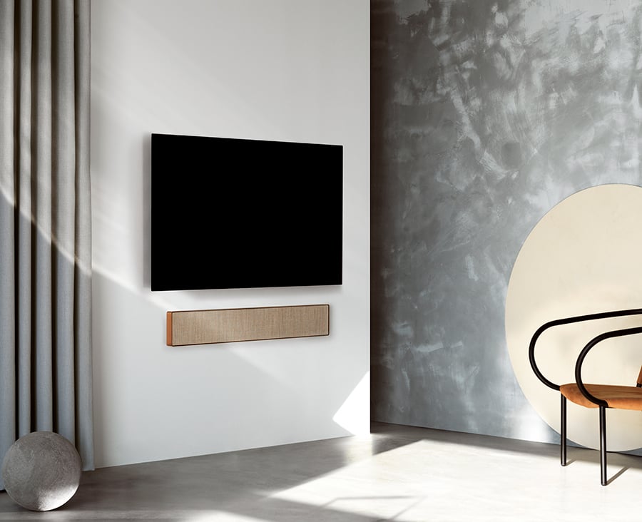 Wandgemonteerde televisie met soundbar in een lichte woonkamer