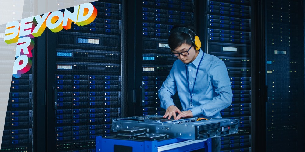 A technician in a blue shirt works at a server rack, adjusting equipment in a data center.