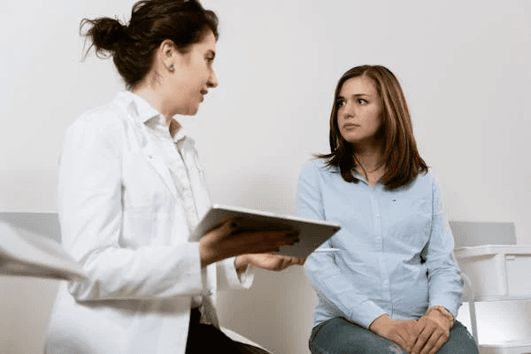 Doctor discussing tax reduction strategies with a patient in a medical clinic, representing tax-saving methods for USA-based medical practices.