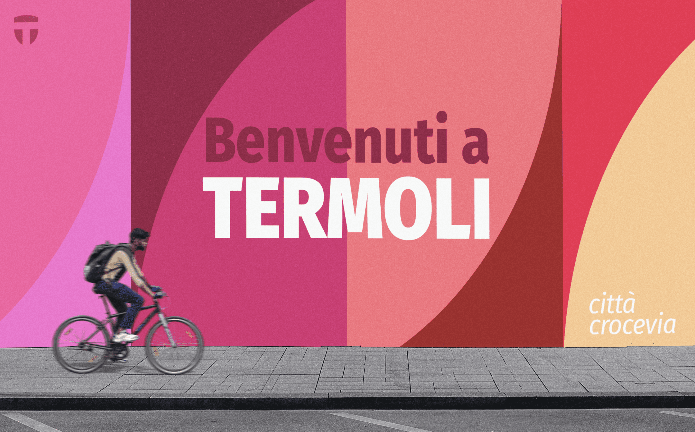 Mockup of the City Branding Termoli project featuring a boy riding a bicycle in front of a colorful mural that says “Benvenuti a Termoli”