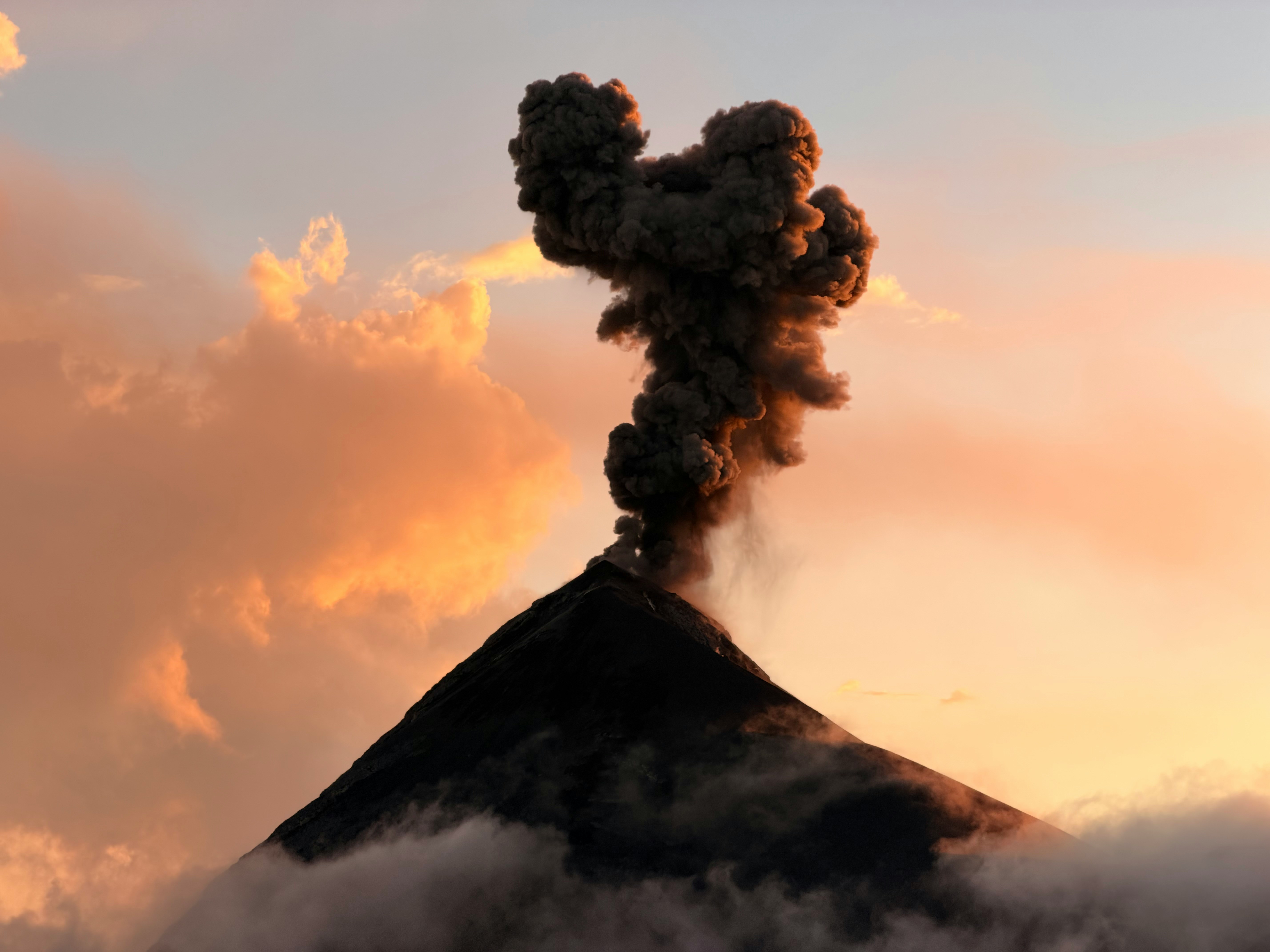 Volcano erupting with smoke and clouds at sunset