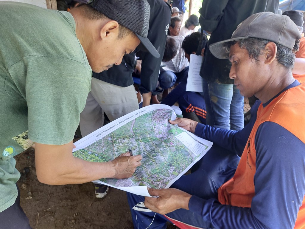 Two individuals focus on a map while seated at a table, surrounded by a busy outdoor setting.