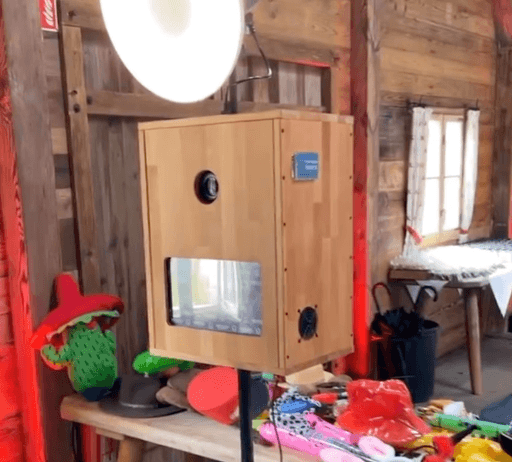 Fotobox aus Holz mit Ringlicht und Requisiten bei Hochzeitsfeier aufgebaut