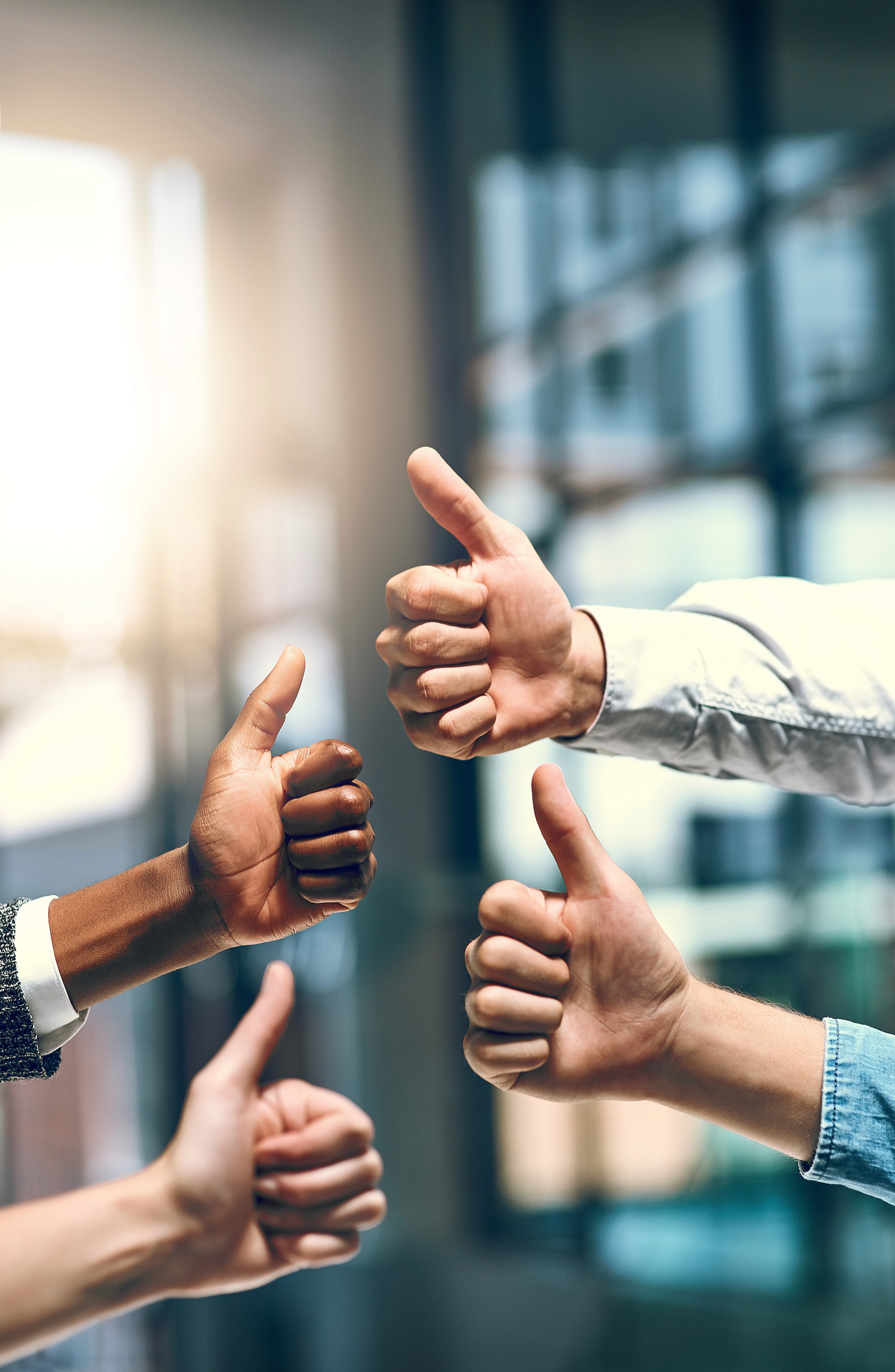 A joyful woman in a textured white blouse laughs in warm sunlight, with a blurred desert-like background adding a serene vibe.