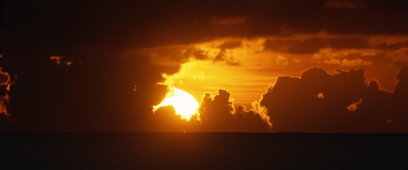 Sunset with a sun partly behind the clouds