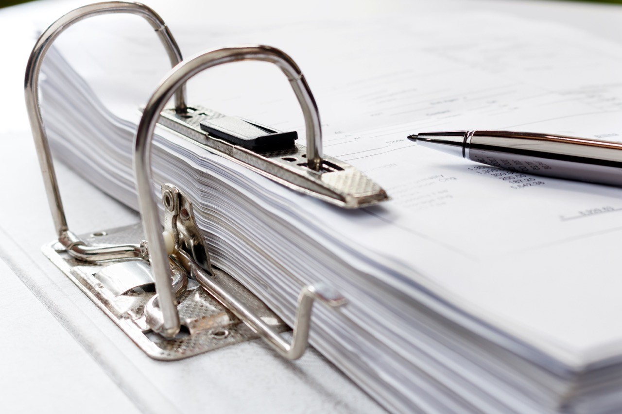 Close-up of an open binder filled with regulatory documents and a pen, emphasizing SAA Law's meticulous attention to detail in regulatory compliance services.