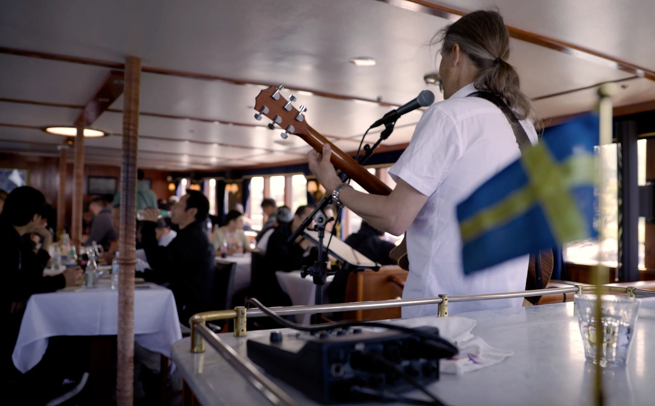 En person som står på en båt och sjunger samt spelar gitarr