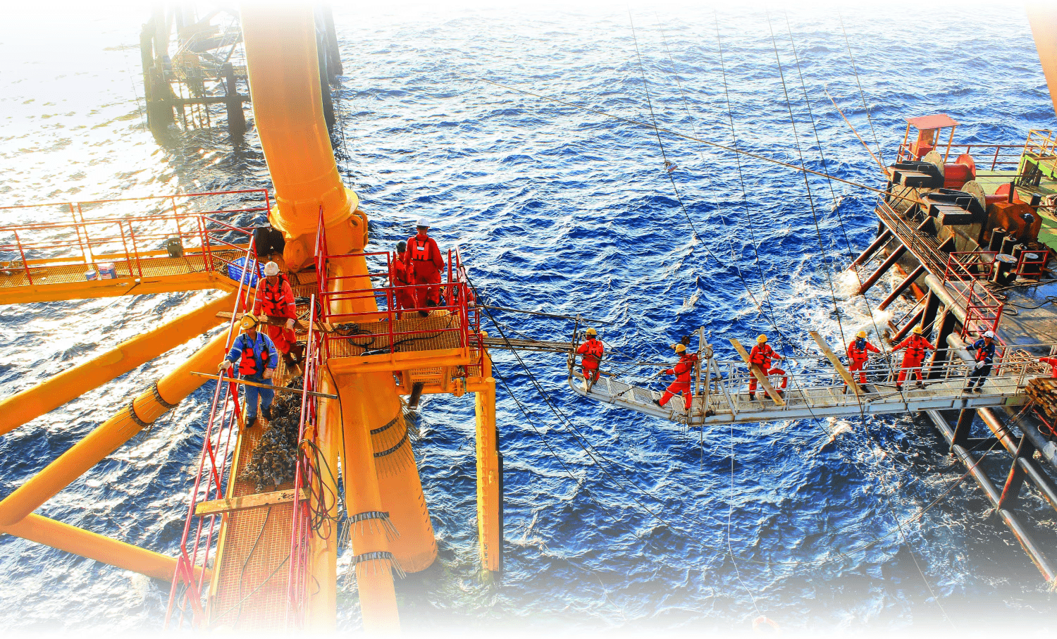 An offshore oil rig with bright orange structures and workers, set against a backdrop of blue ocean and sky.