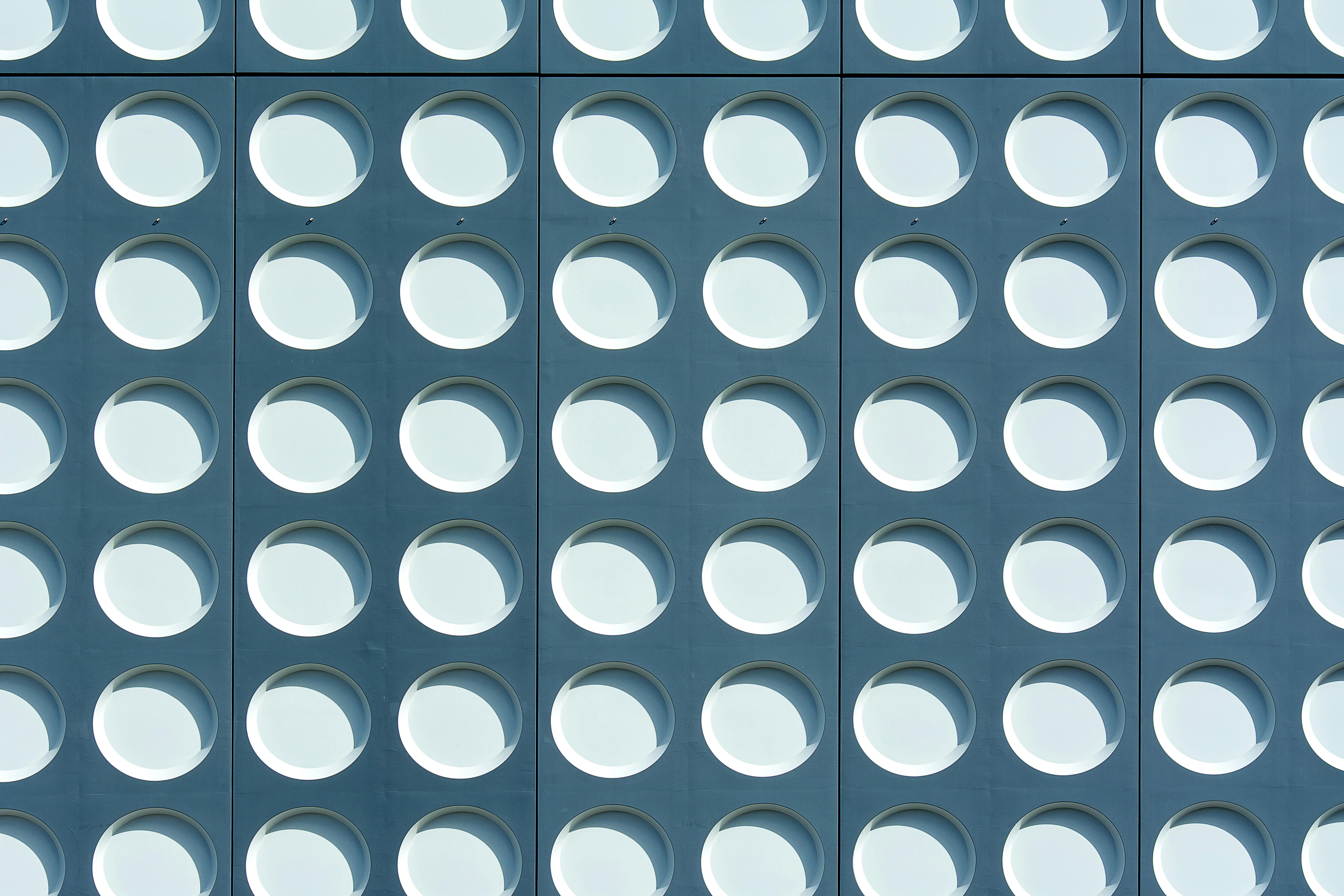 A minimalist architectural scene featuring smooth white curved structures framing a clear blue sky, with clean lines and soft shadows creating an abstract, modern composition.