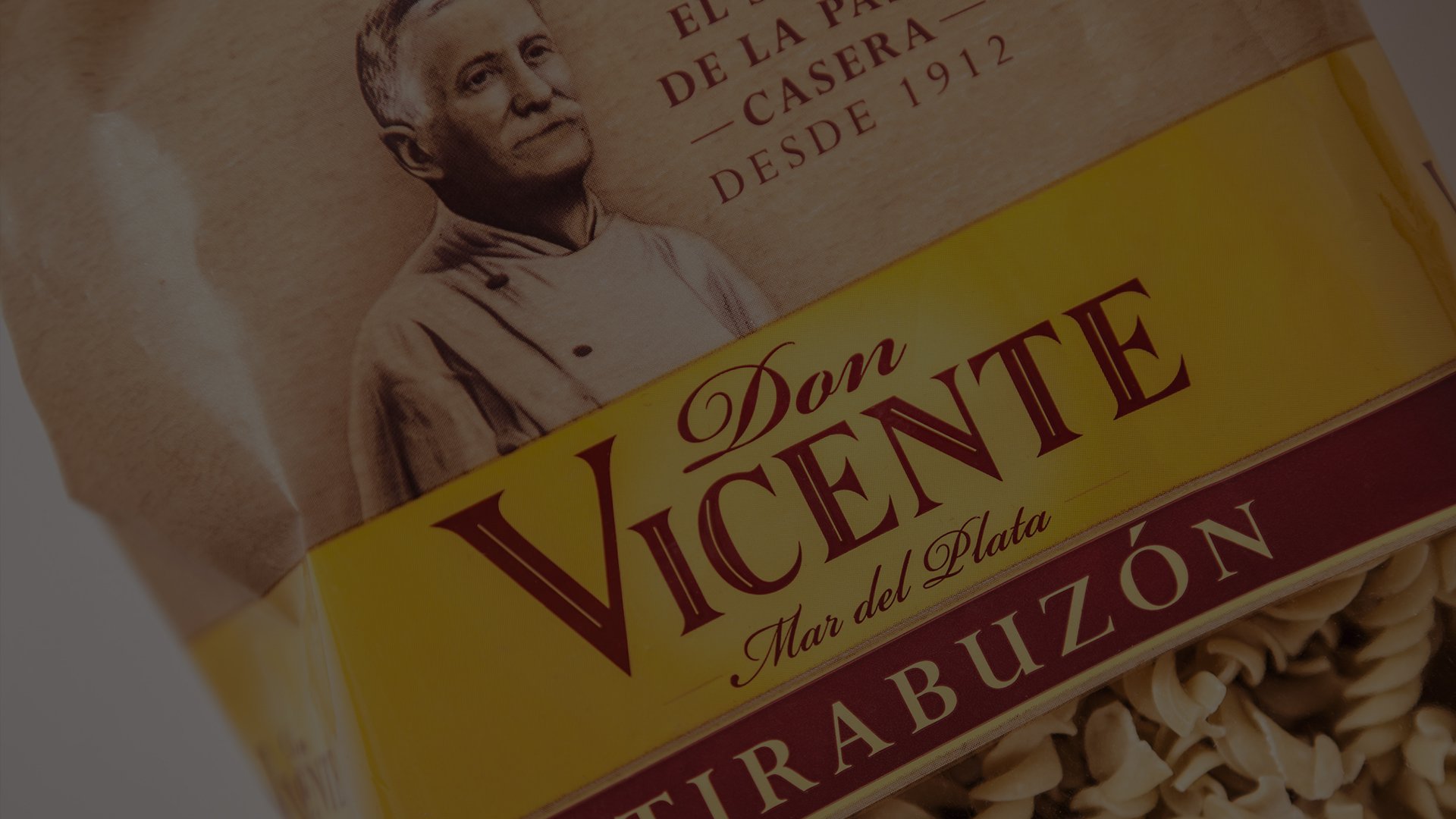 Pasta package labeled "Don Vicente, Mar del Plata" with an image of an elderly man, conveying tradition. Yellow and red text on a clear bag showing pasta.