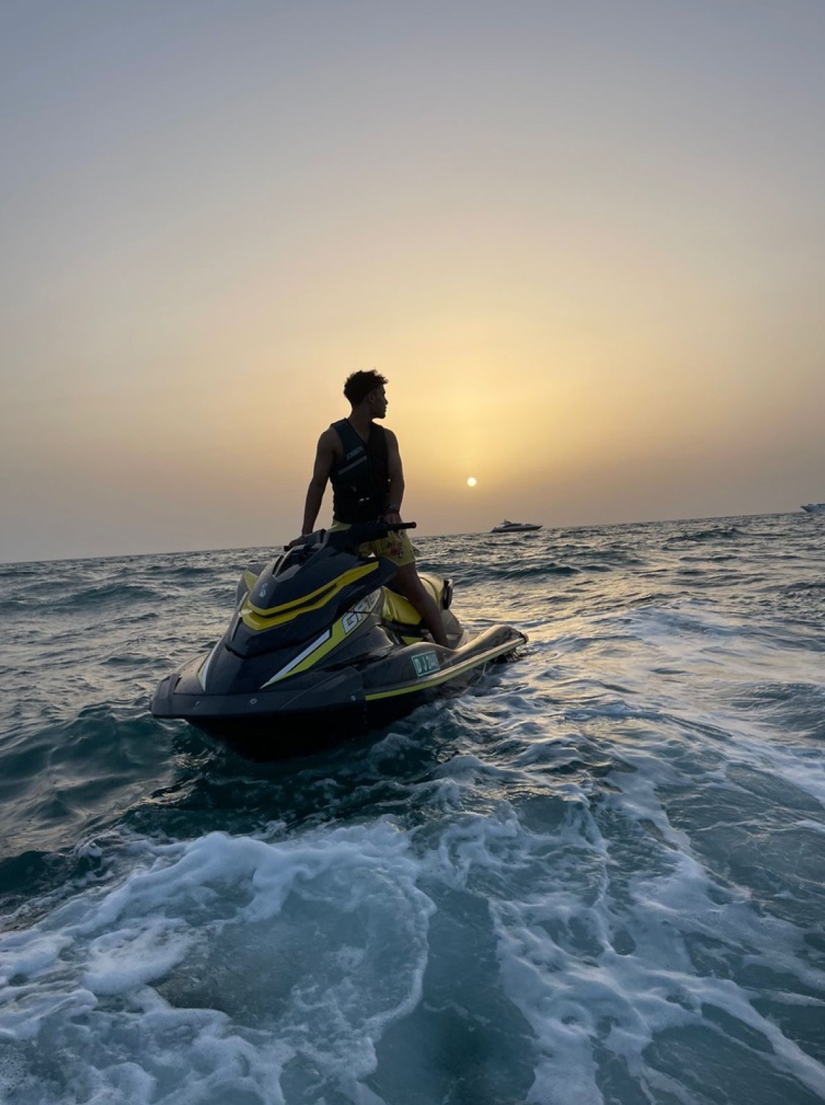 Man and young boy enjoying a jet ski ride on a yellow Yamaha near Burj Al Arab, Dubai.