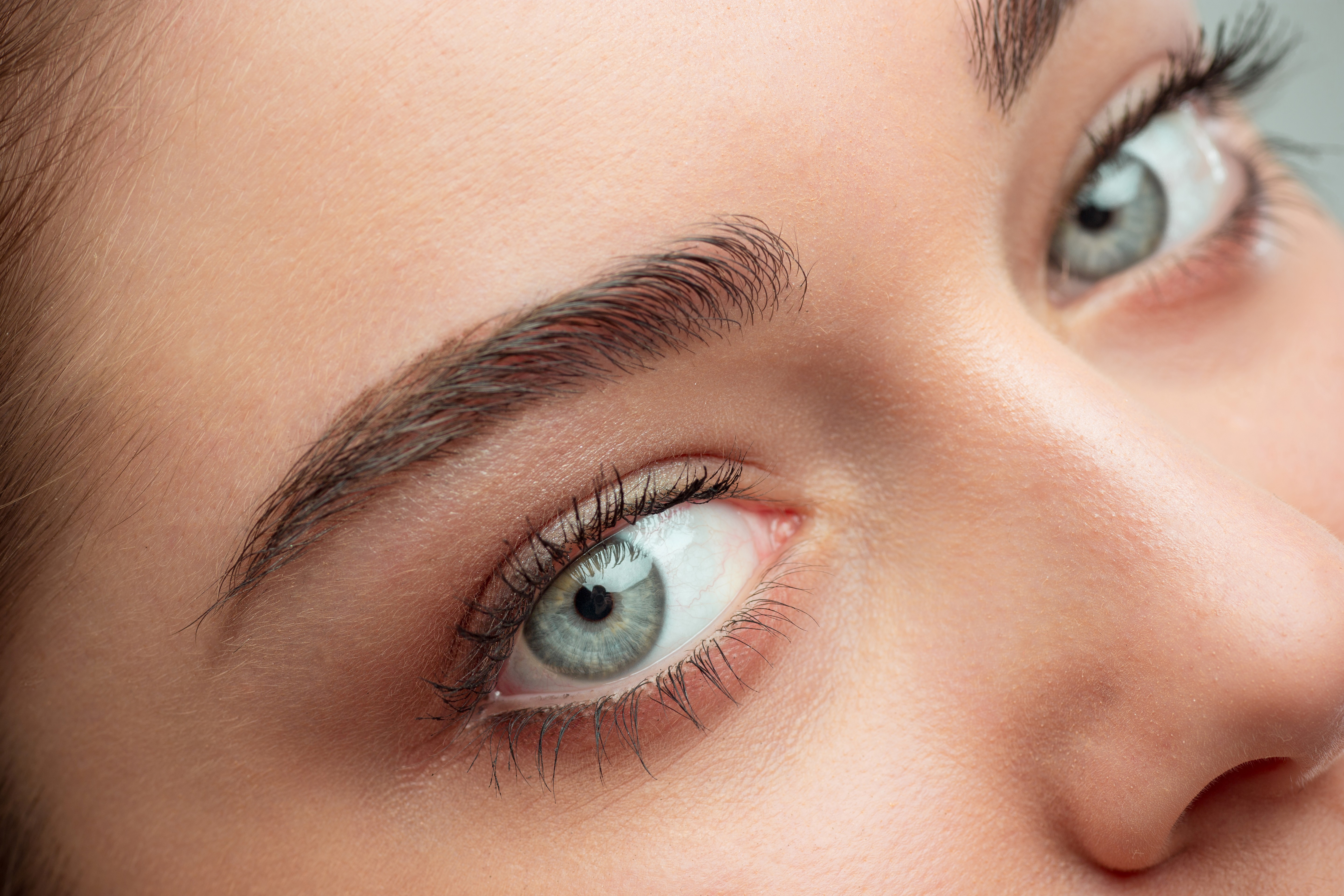 Close-up of a woman's face showcasing healed combo brows, a blend of microblading and shading for a natural yet defined look.