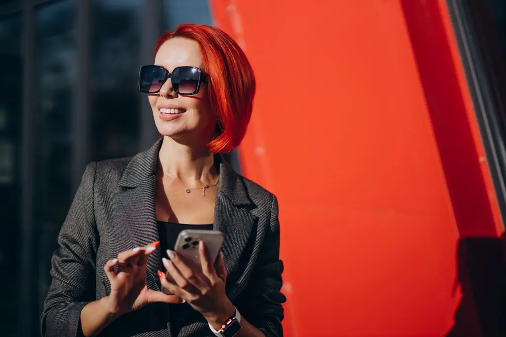 femme entrepreneure à la mode souriante avec des lunettes de soleil et veste grise