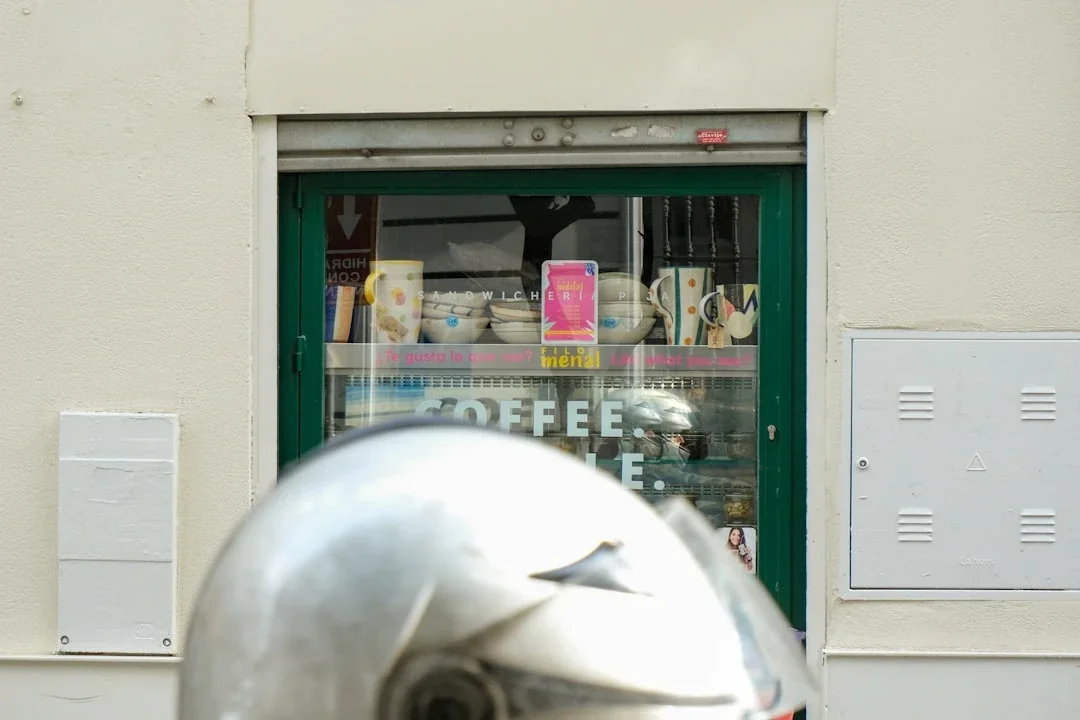 Silver helmet in front of a coffee shop window.