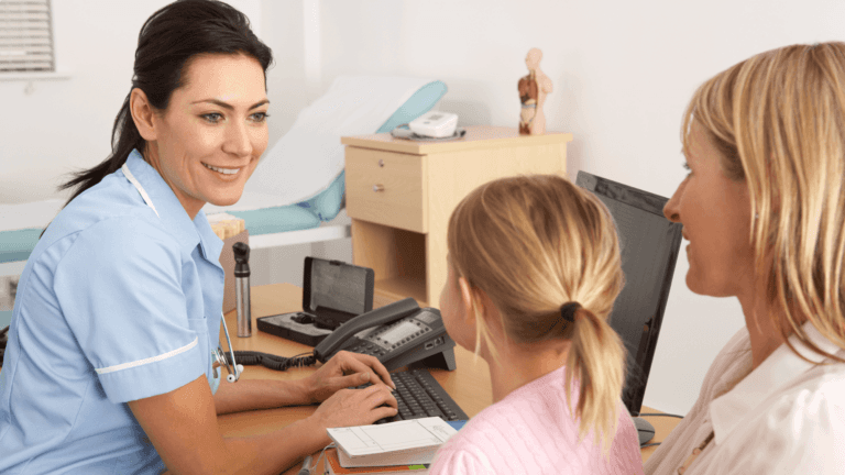 A nurse in blue scrubs interacting warmly with a patient or child in a healthcare setting