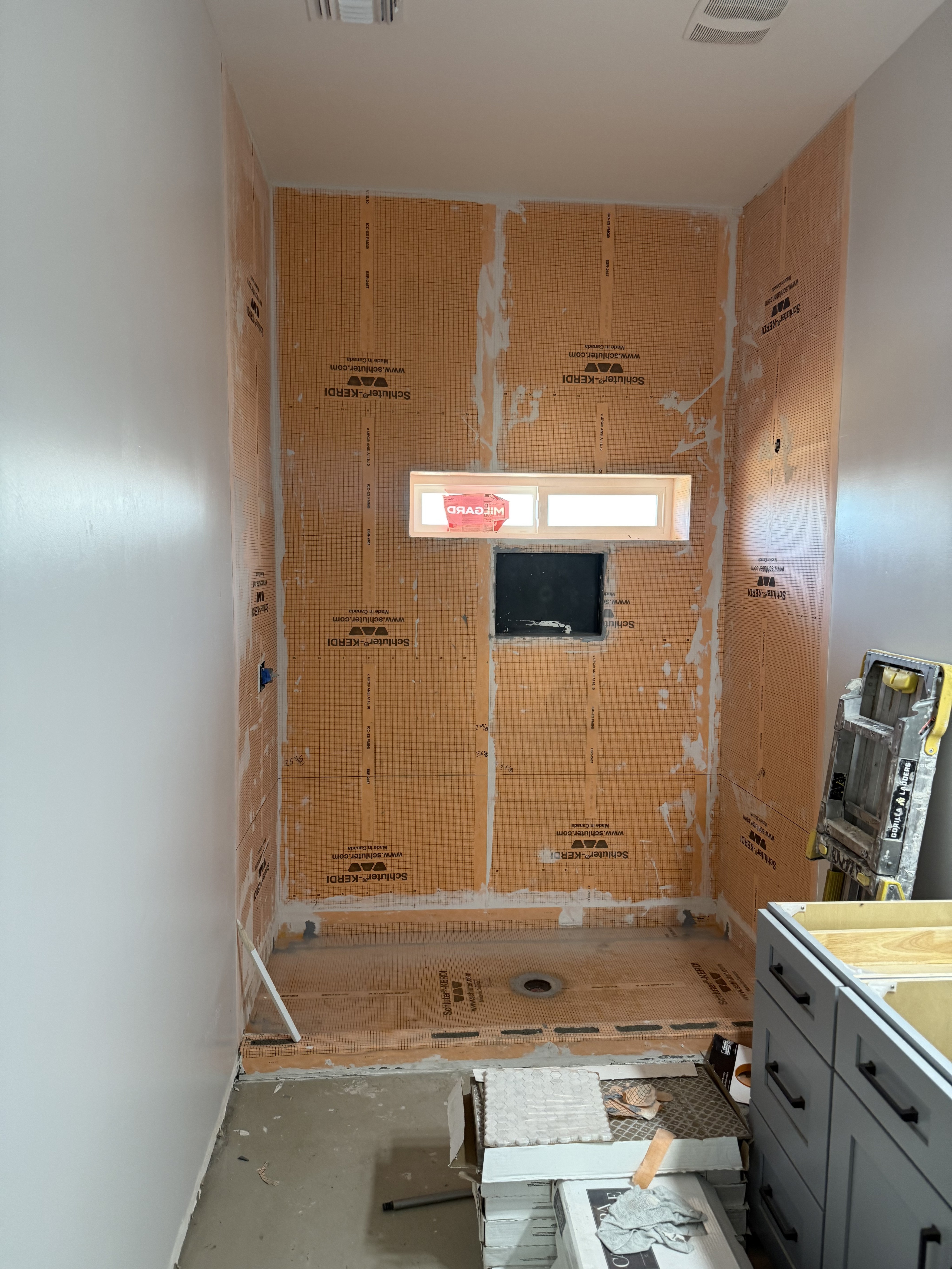 Bathtub shower combo with sleek grey marble-look large format wall tiles, a built-in shower niche with a white and grey hexagonal mosaic tile accent, and modern chrome fixtures.
