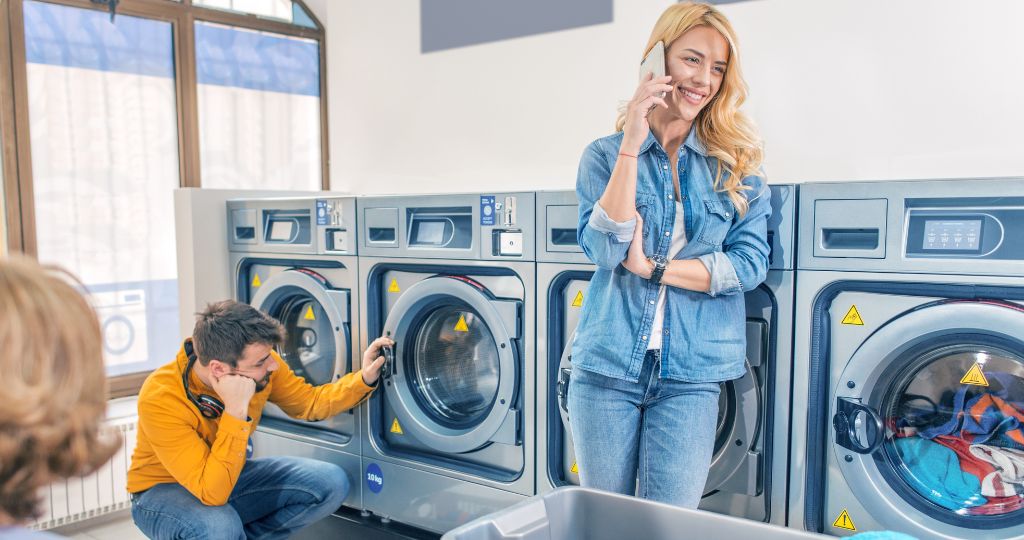 Laundromat scene with a woman on the phone and a man checking a machine