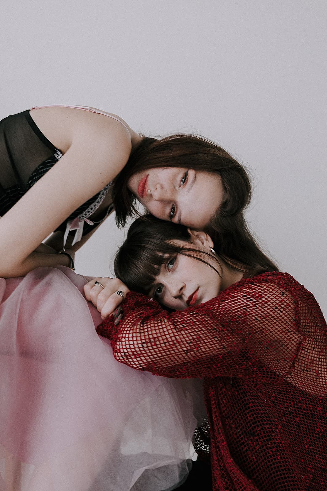 Two models, one in a black dress and the other in a pink tulle skirt, leaning on each other during a 90s vintage-inspired photoshoot at Revelator Studio in Shreveport.