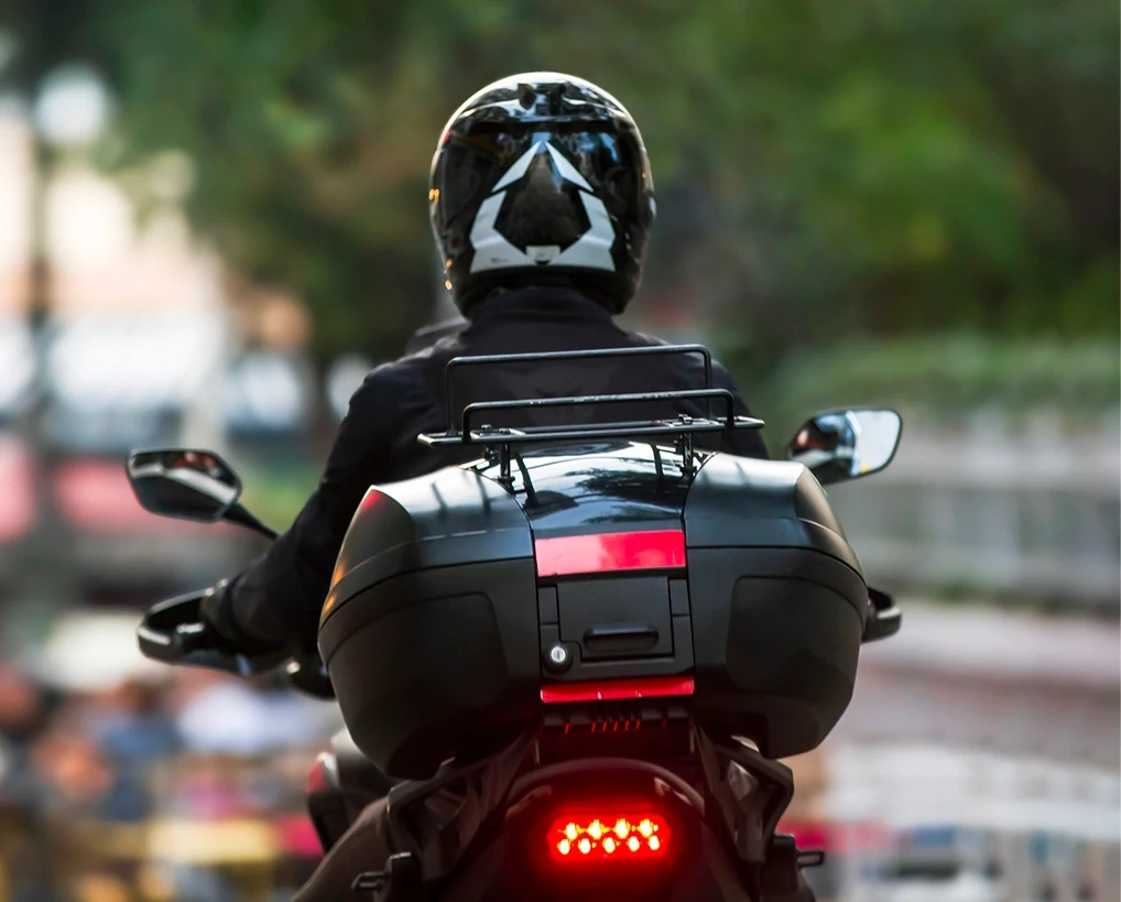 Rear view of a helmeted motorcyclist riding on the road, illustrating motorcycle crash cases in Stockton