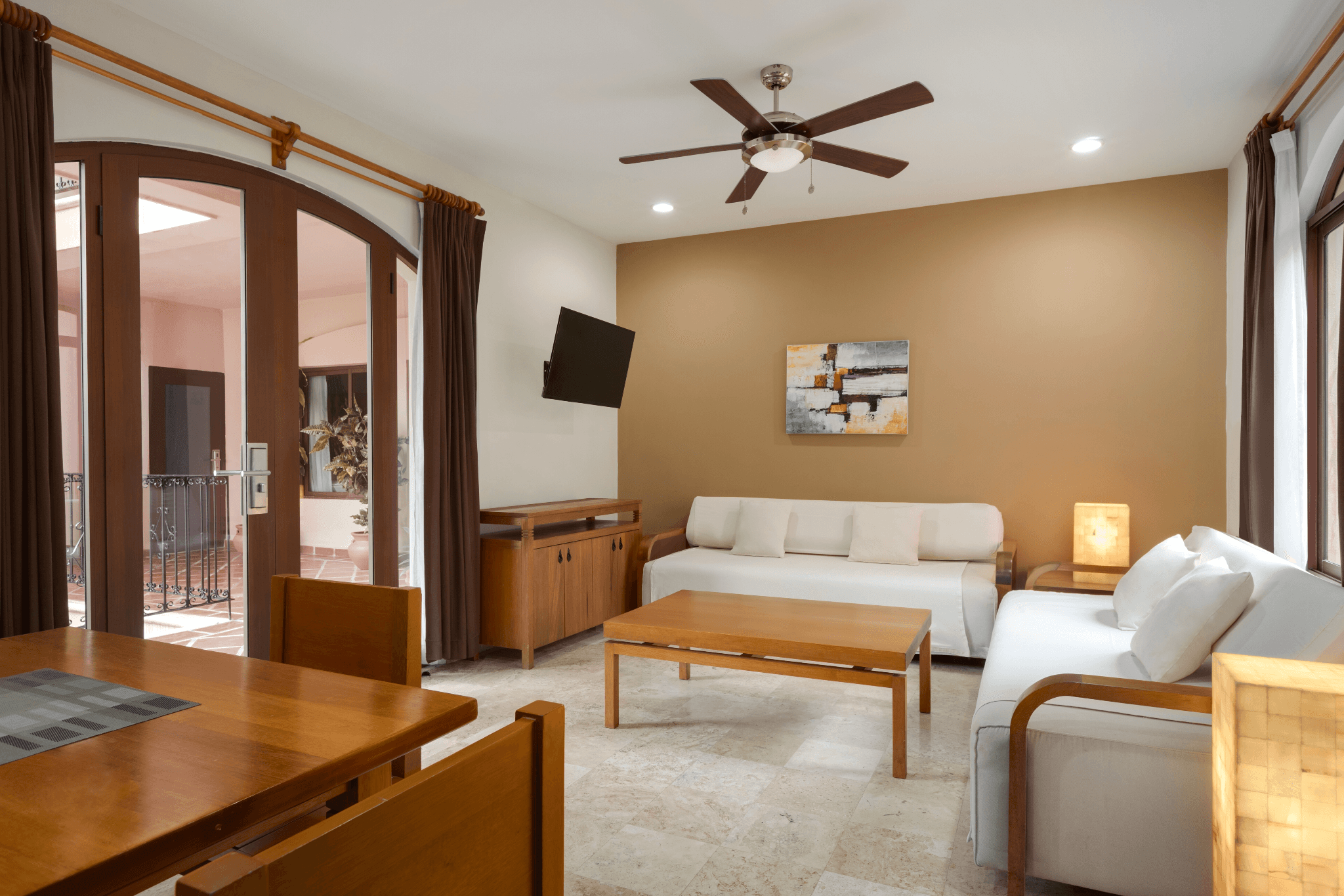 Spacious Acanto hotel suite with living area, dining table, and private balcony doors.