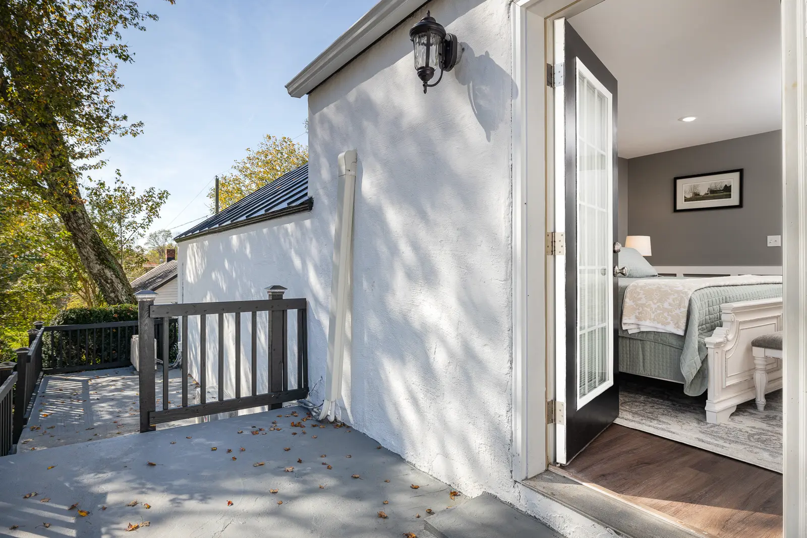 Outdoor patio with an open door revealing a bedroom with a bed.
