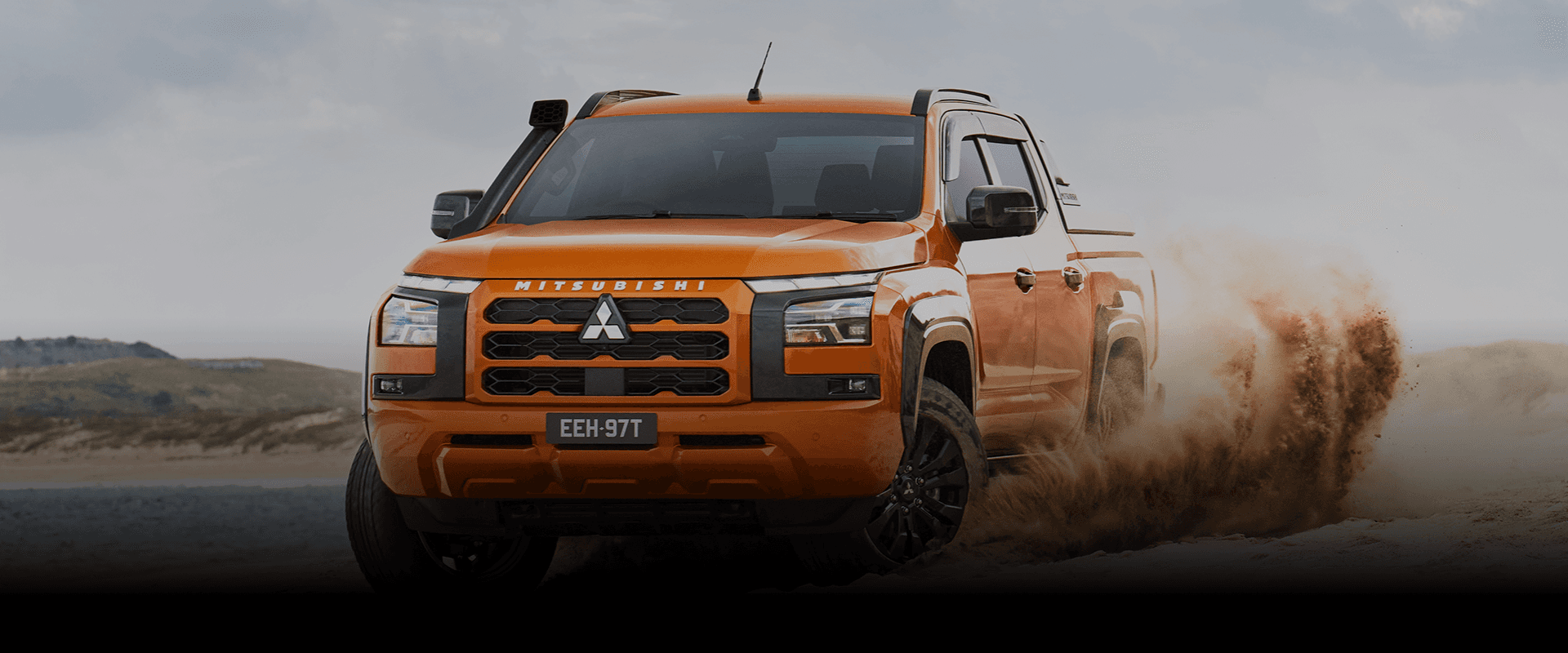 Orange Mitsubishi triton car driving in terrain