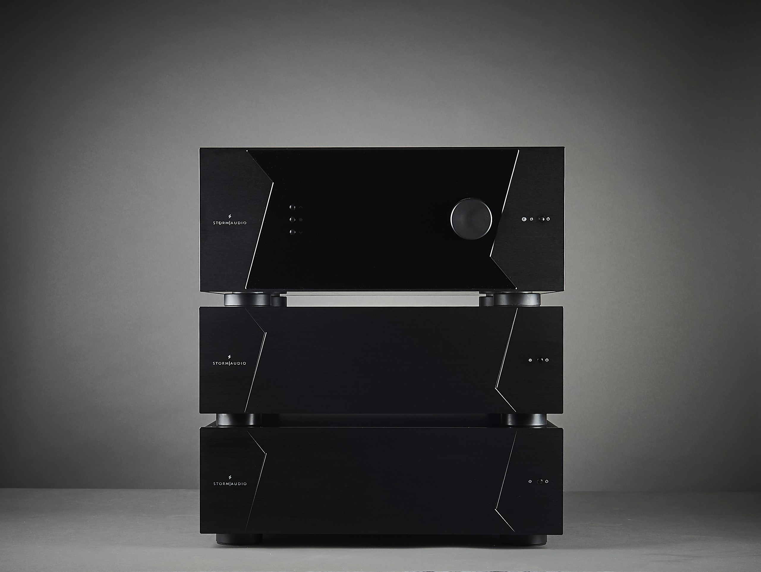 Black audio amplifiers stacked on a gray surface.