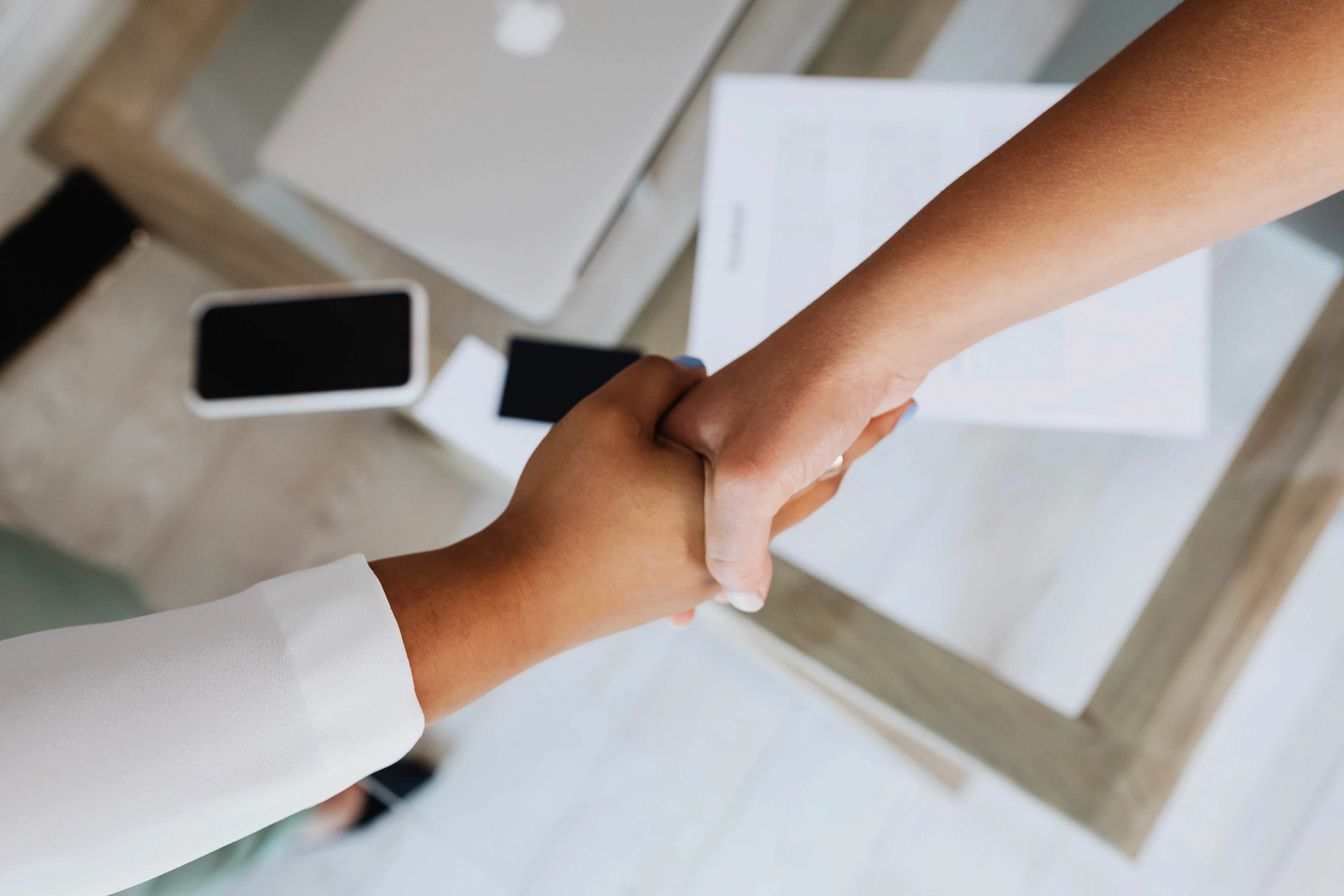 Two professionals sealing a deal with a firm contract handshake, symbolizing agreement and trust in a business partnership.