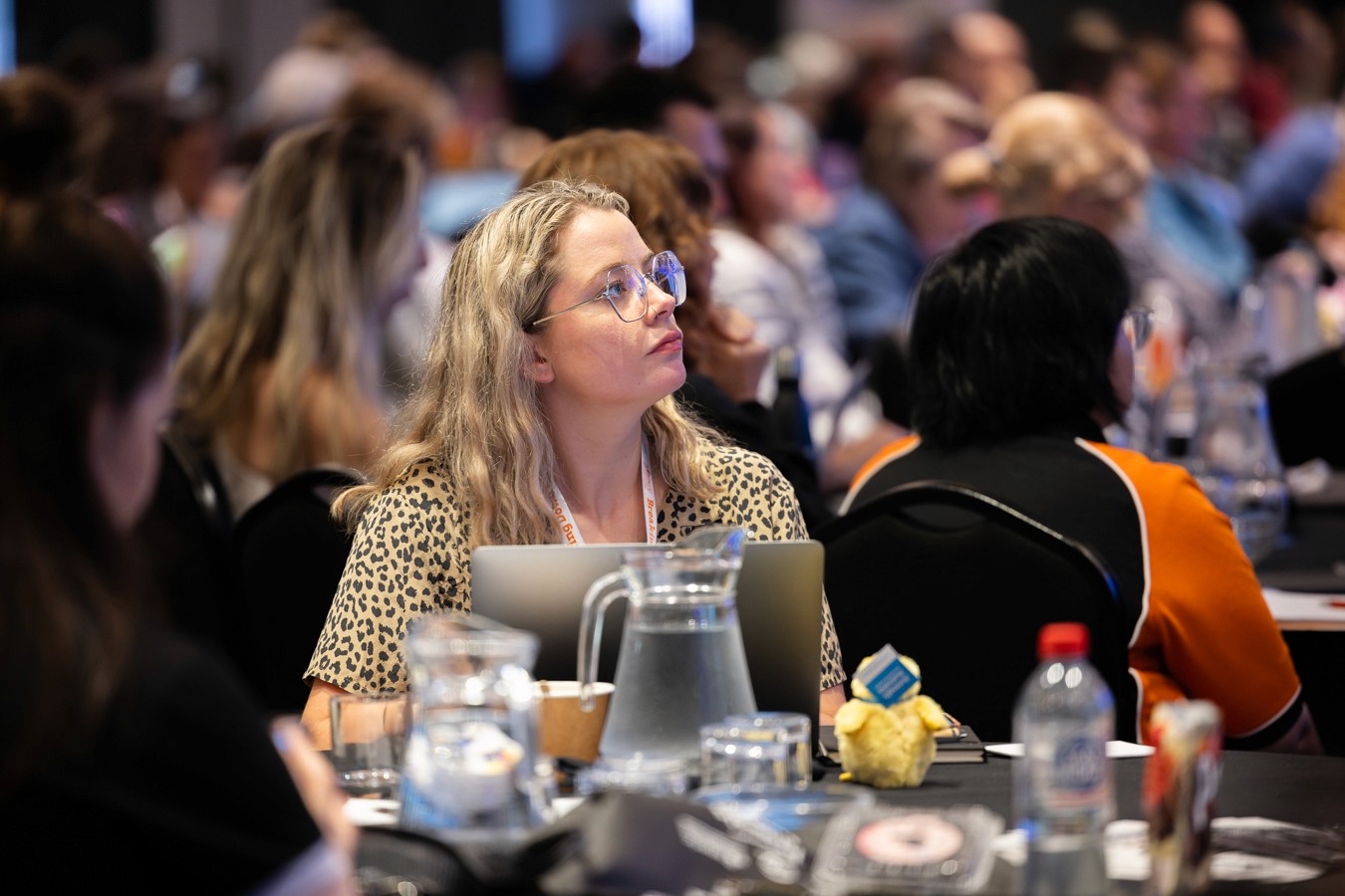 Woman sitting at conference looking up from her laptop