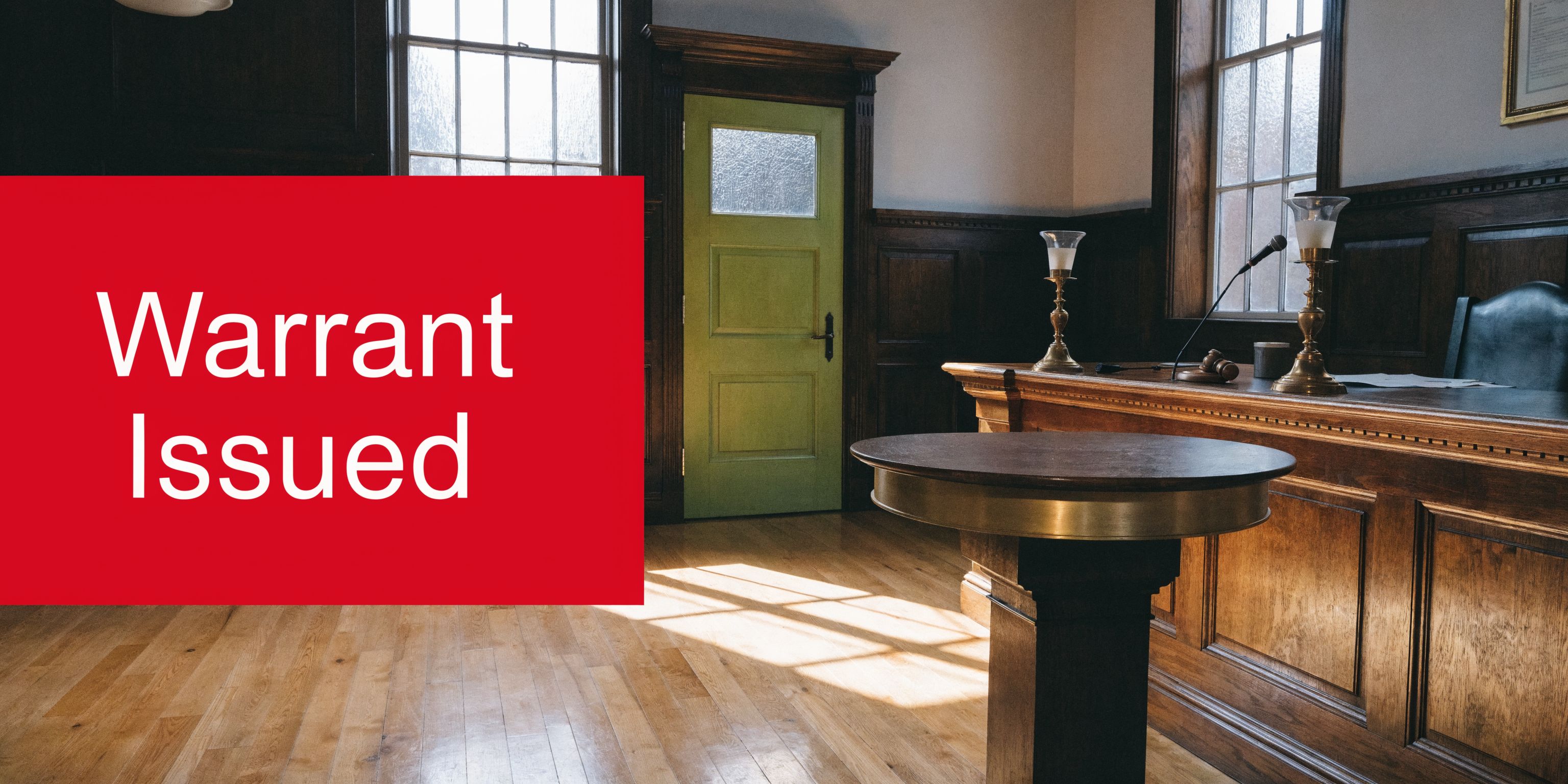 An empty courtroom featuring a wooden judge's bench and a red text overlay reading Warrant Issued.