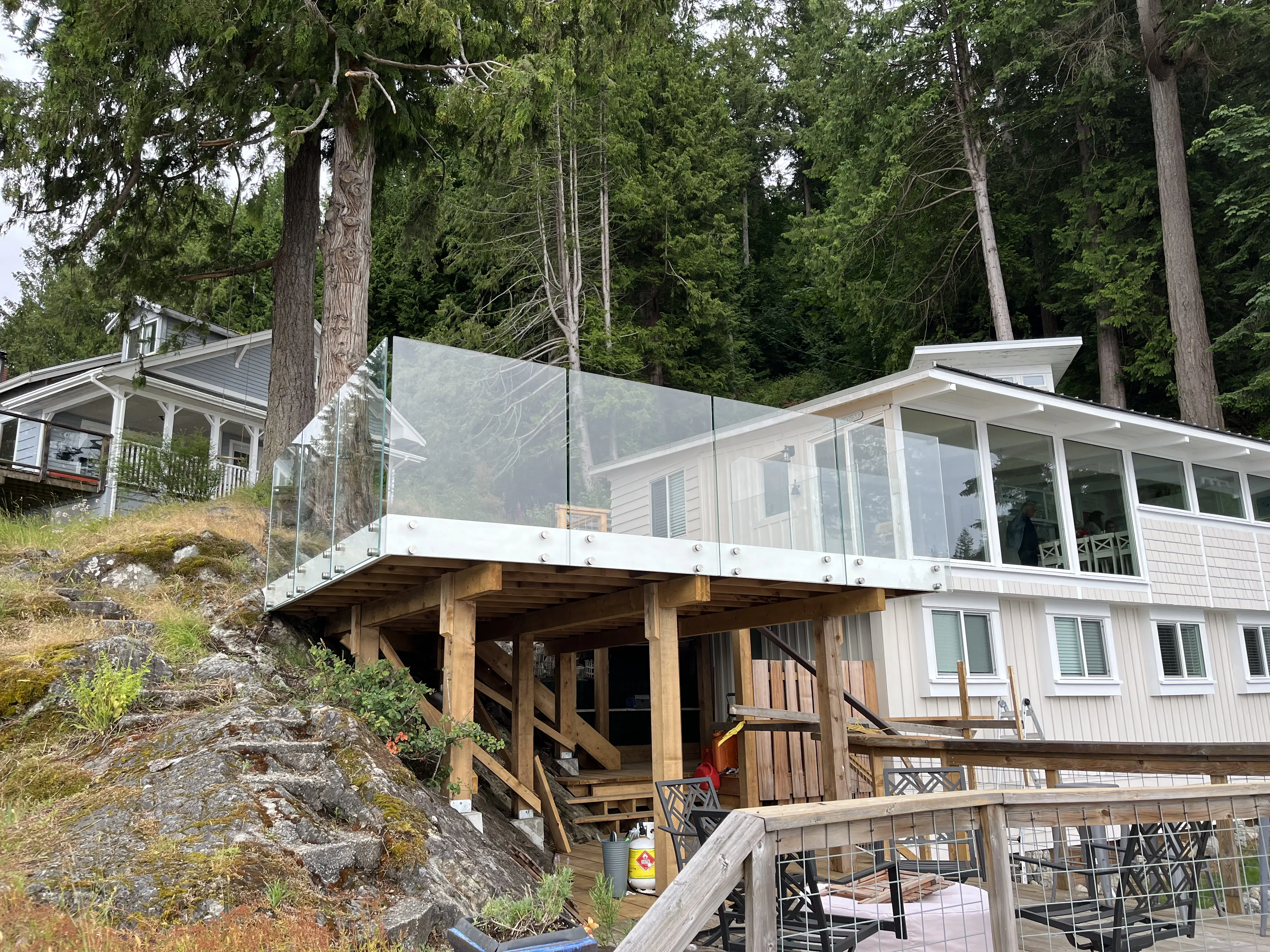 Frameless glass railing on an elevated deck overlooking a forested BC hillside