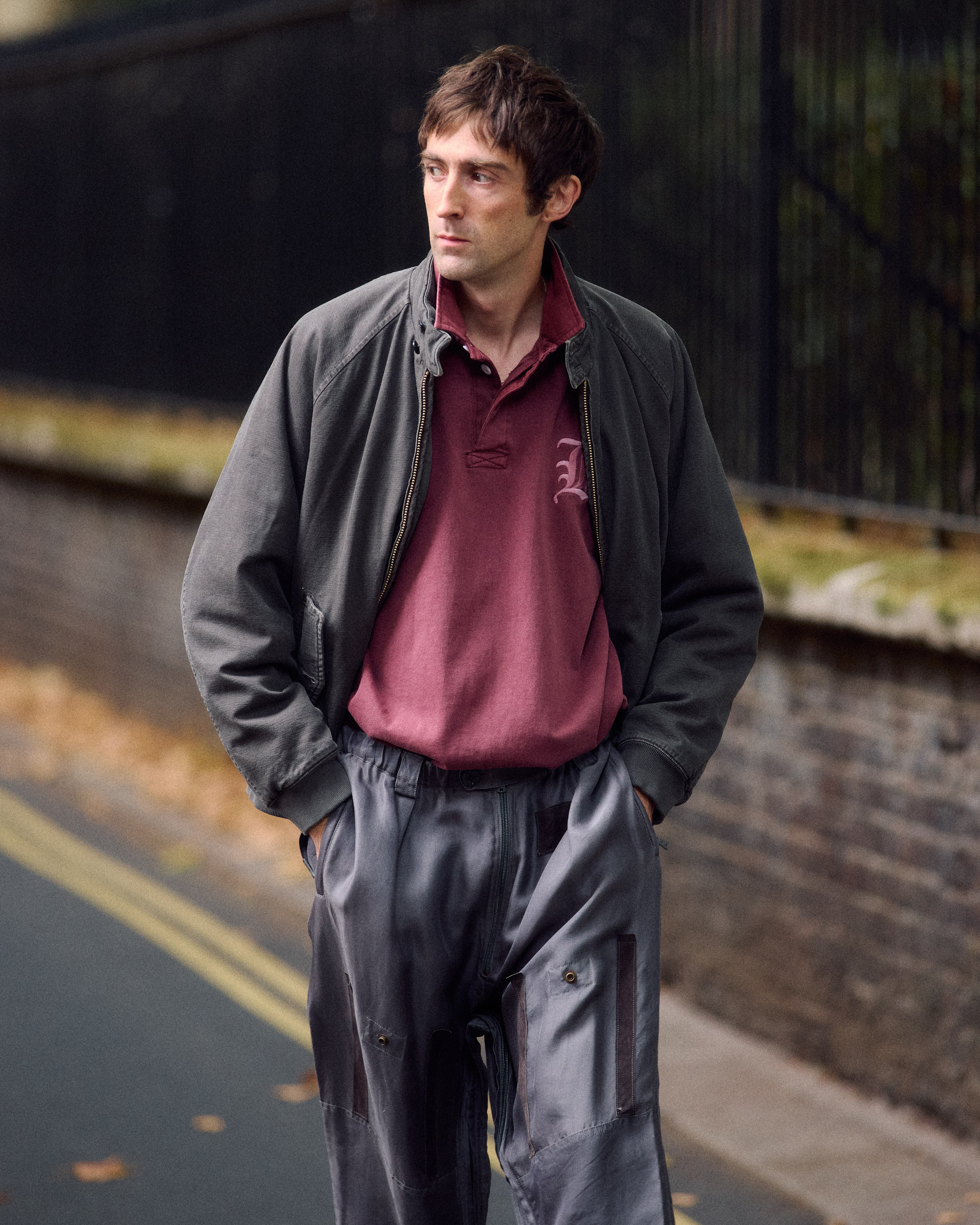 Le mannequin porte un blouson gris en coton lavé oversize, un polo bordeaux et un pantalon large