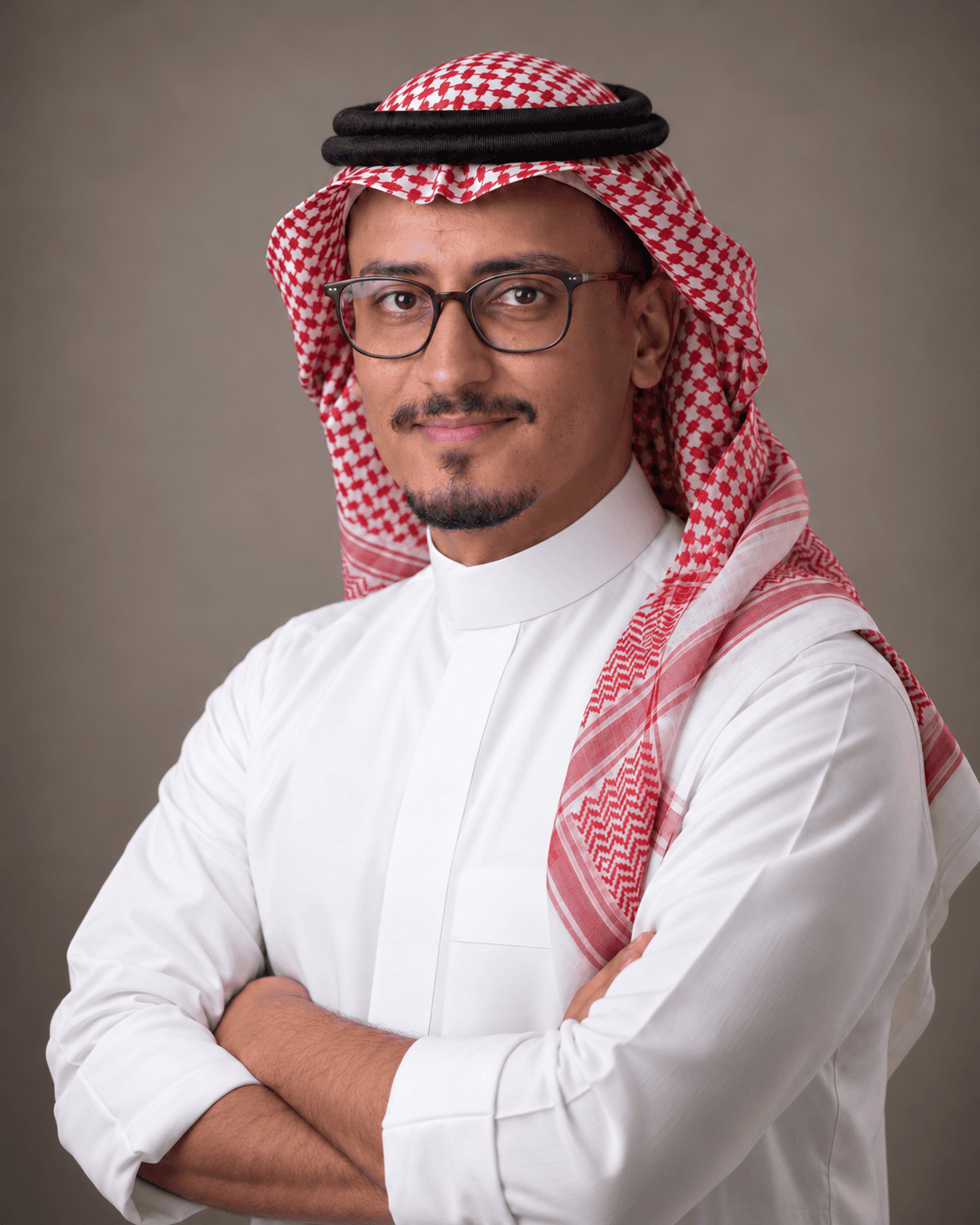 Natural studio portrait of Ammar in a white thobe and red-and-white shemagh