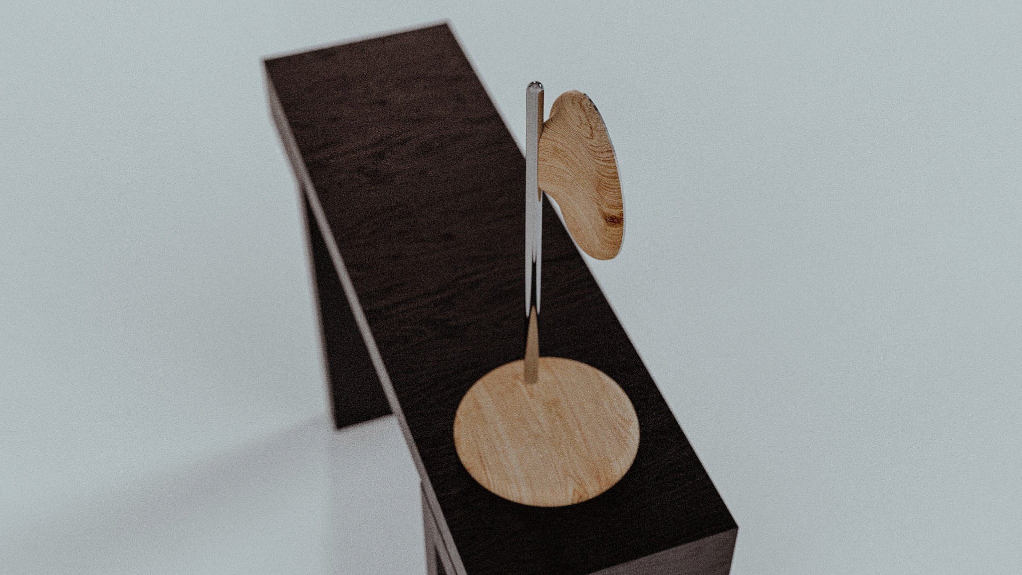 An abstract wooden art piece consisting of circular shapes and a stand, displayed in a minimalist setting.