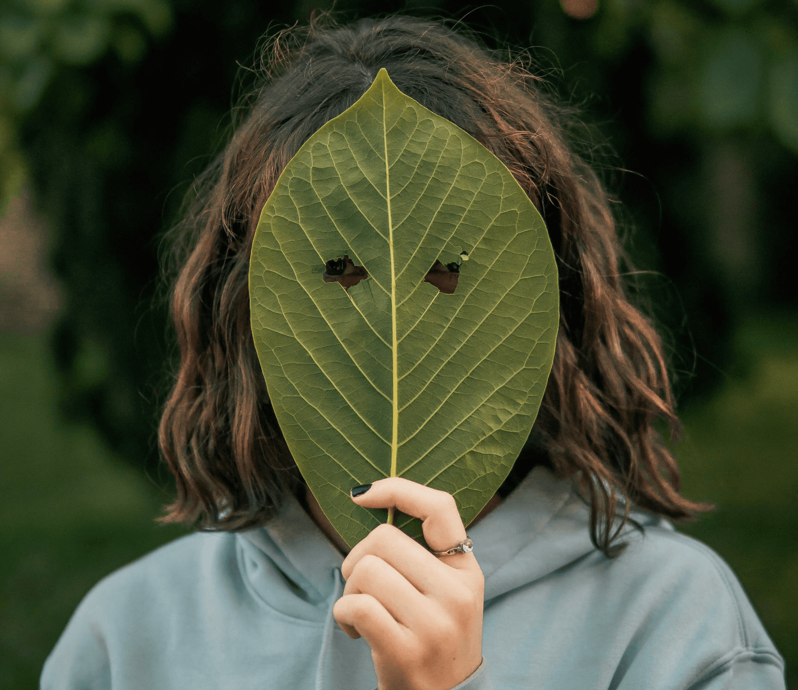 woman in gray long sleeve shirt holding green leaf
