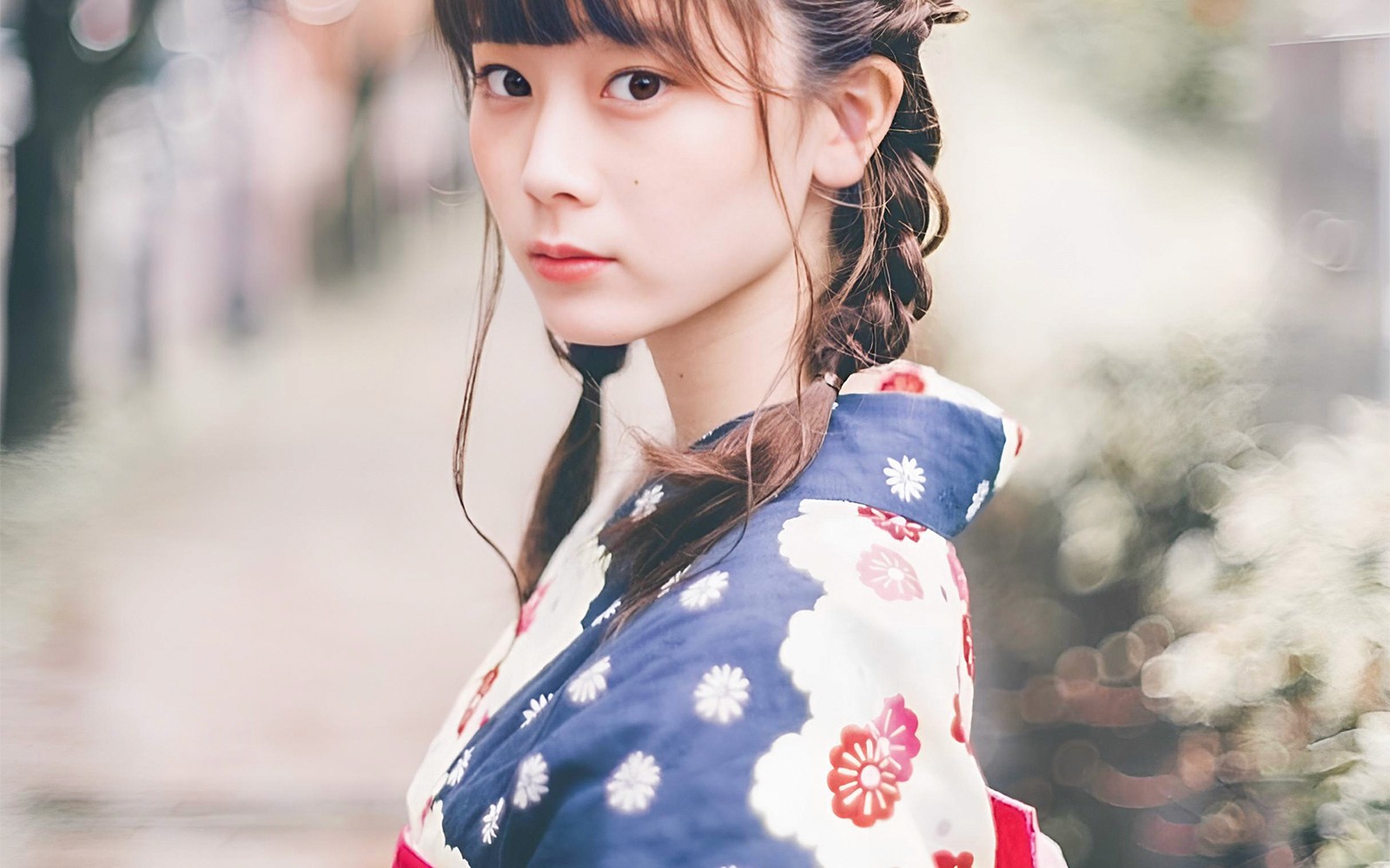 Woman in traditional kimono walking through Asakusa, Tokyo with Senso-ji Temple in the background.