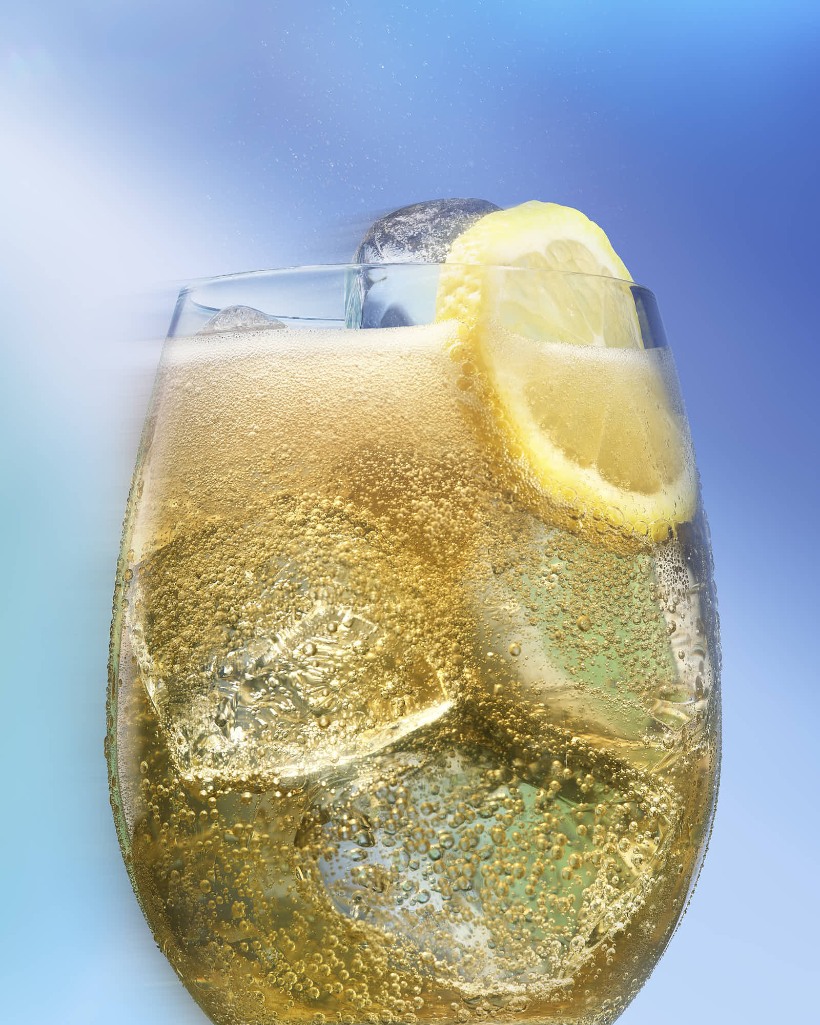 A refreshing drink in a glass with ice, garnished with lemon slices, set against a blue background.