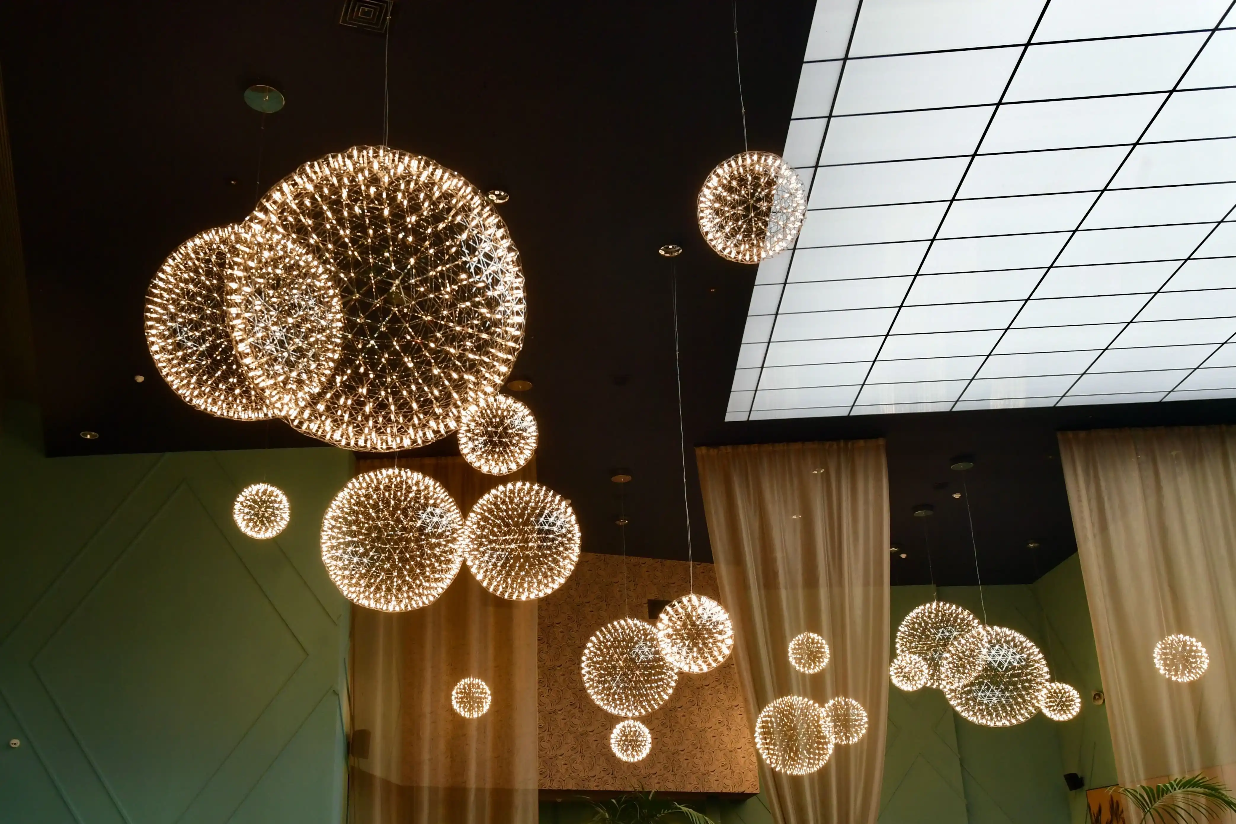 Artistic lighting fixture featuring glowing glass spheres suspended near a stone architectural feature.