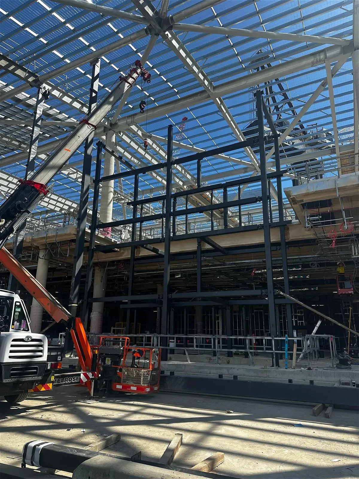Construction site with cranes and steel framework.