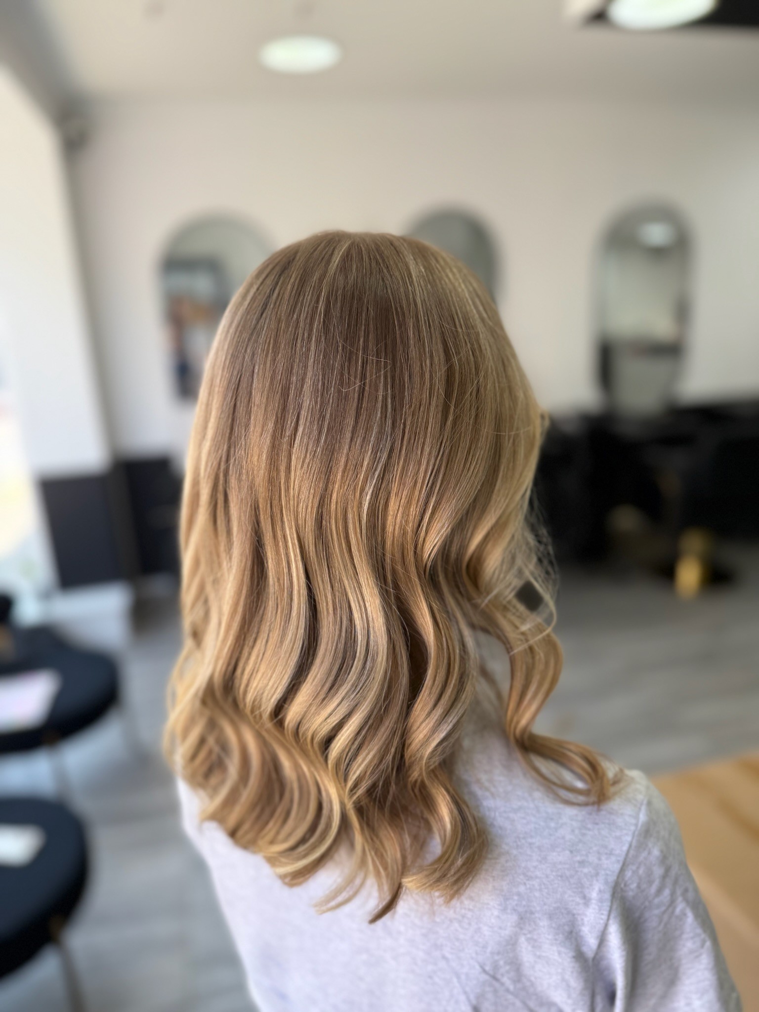 Woman with long wavy blonde hair with purpler highlights at Inspire Studio Salon