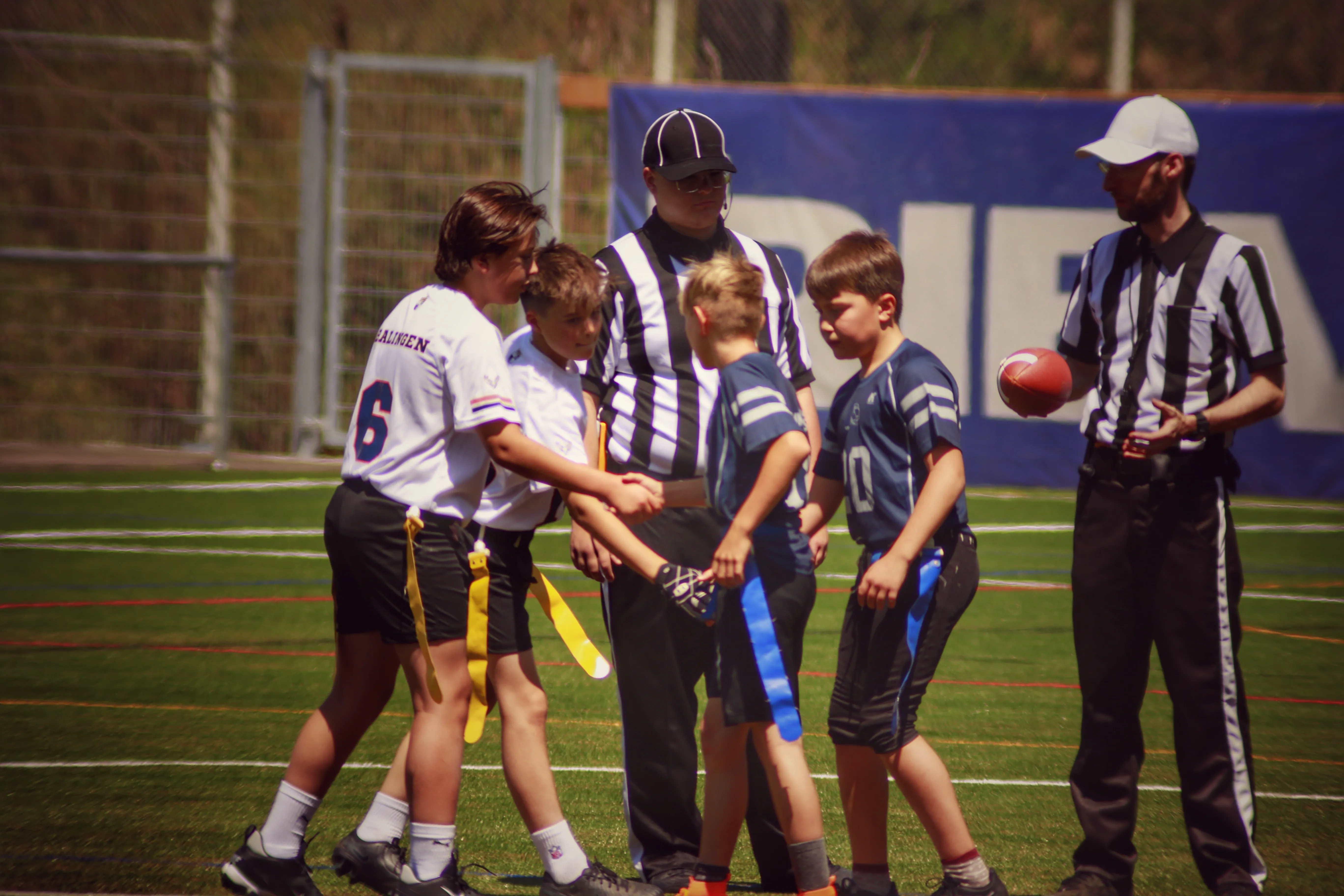 A group of children and referees gather on a sports field, preparing for a game. Excitement is in the air.