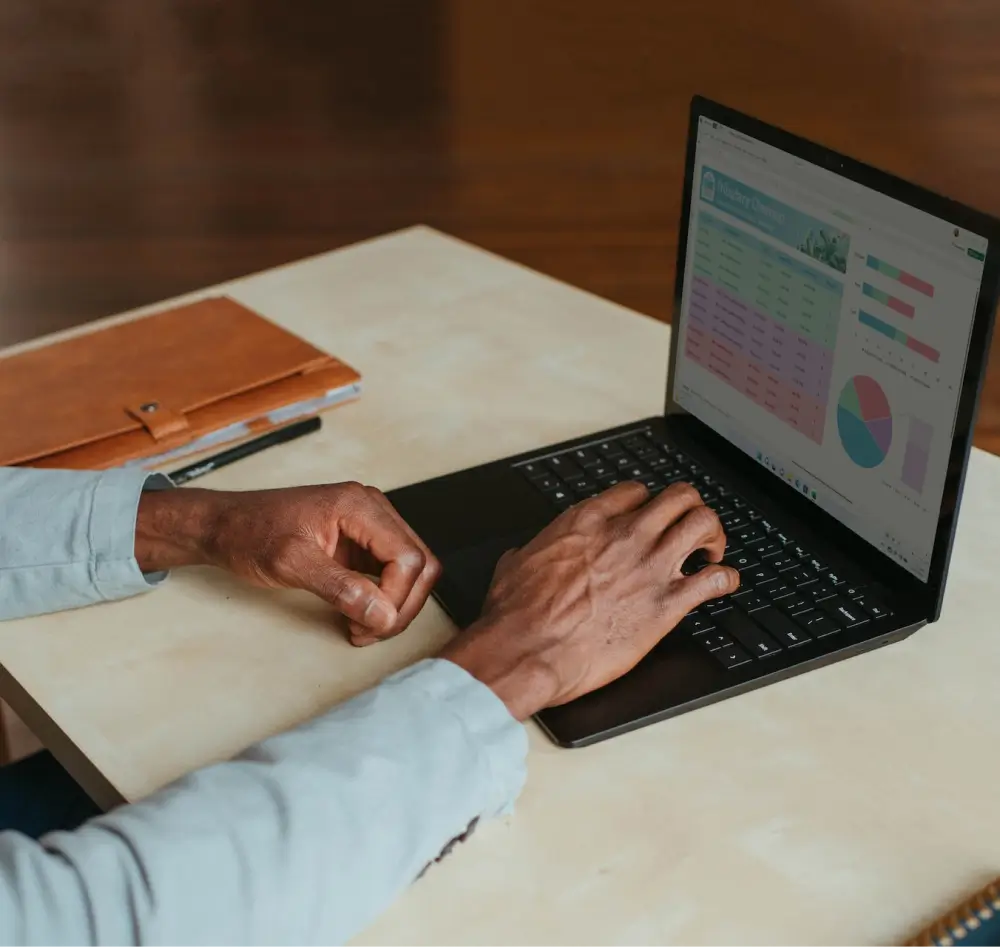 Photograph of hands using a laptop with charts on the display