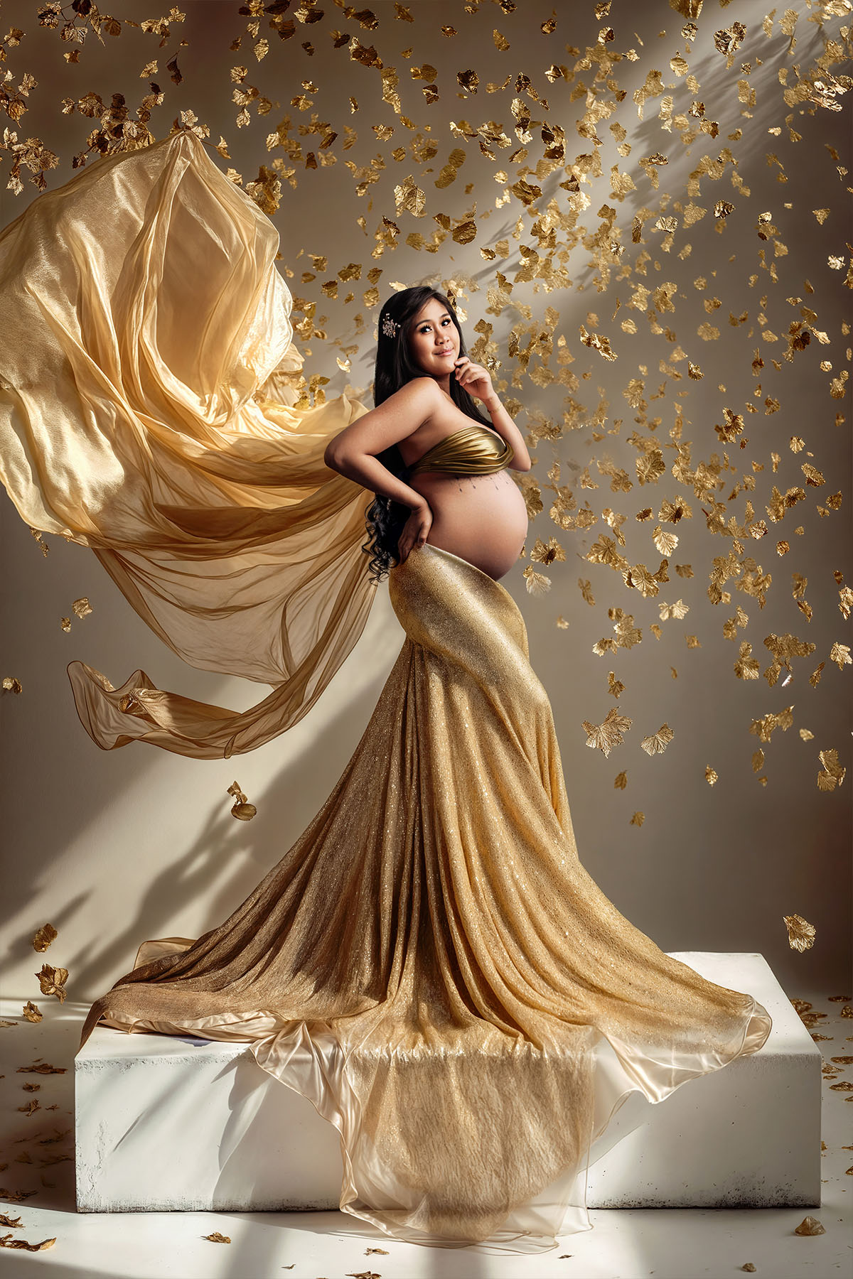 Maternity photoshoot with flying silk gown — dramatic and elegant studio look.