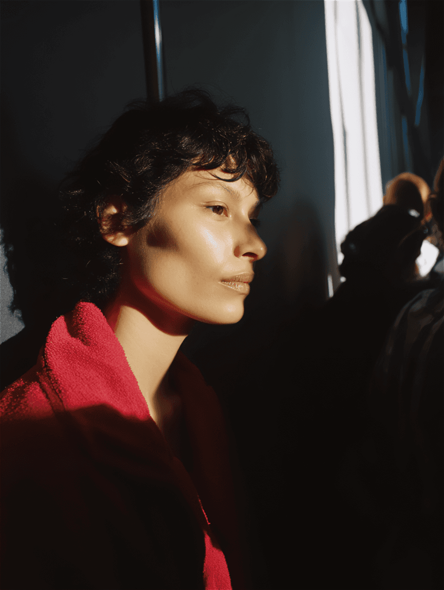 Close-up portrait of a person in dramatic lighting, wearing a red robe, with sharp features and a contemplative expression.