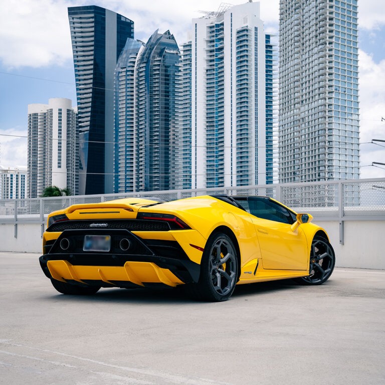 Rear 3/4 view of a yellow Lamborghini Huracán EVO Spyder, highlighting its sleek lines and performance exhaust.