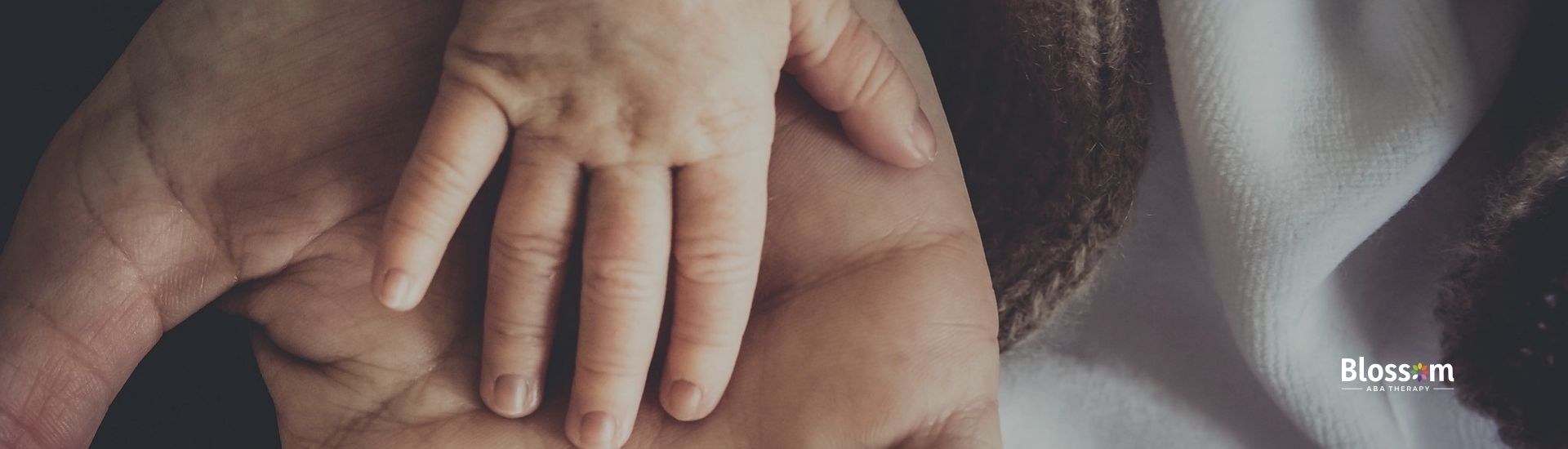 A hand of a baby on top of an adult hand.