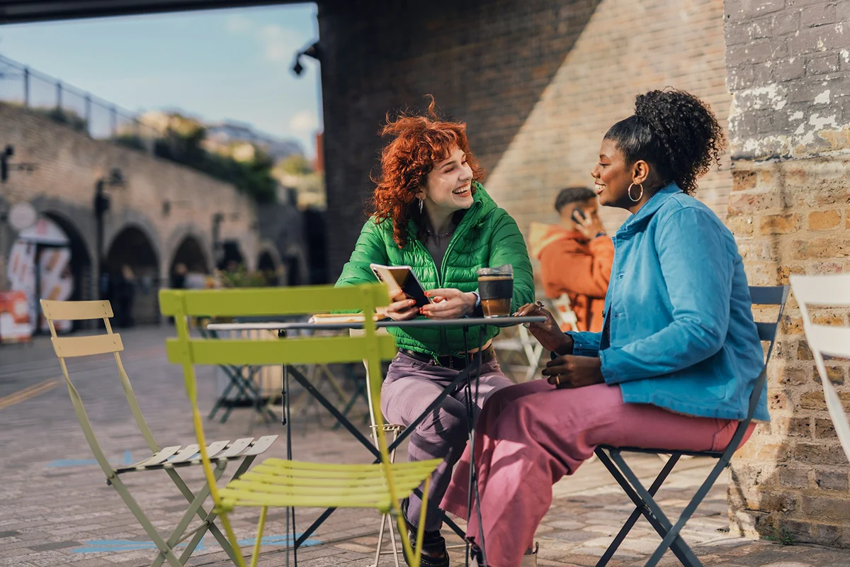 Two people talking at an outdoor cafe table.
