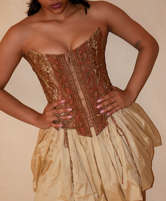 Raina is our one-of-a-kind four-panel corset, handcrafted in-house using a brown ptrinted vintage silk saree. The structured silhouette features V-cut detailing at the front, along with lace-up panels on both the front and back, allowing for a flexible fit that beautifully cinches and shapes the body. Raina is a quiet ode to craft, care, and conscious making.